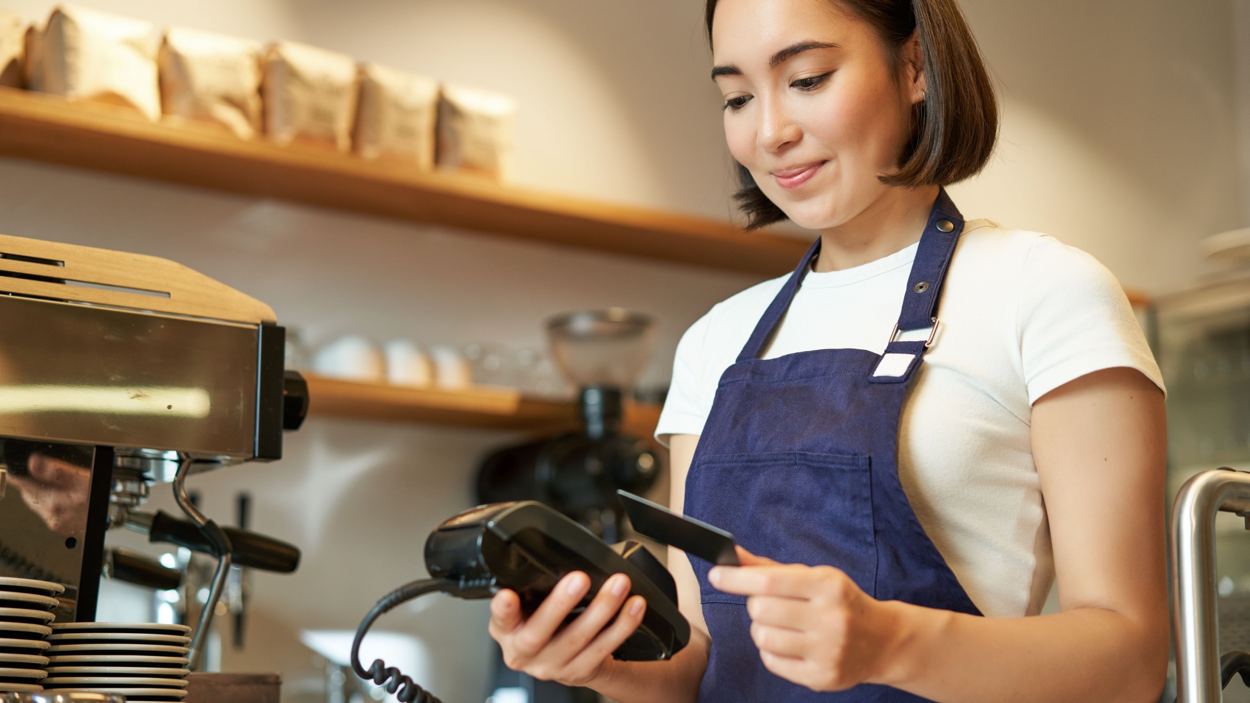 Cute asian girl, barista in cafe processing contactless payment, insert credit card into POS terminal, taking order in cofee shop.