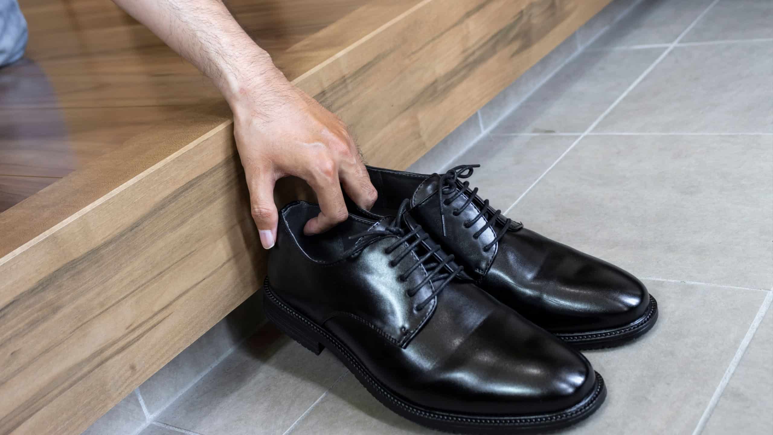 Male hand lifting business shoes at the entrance