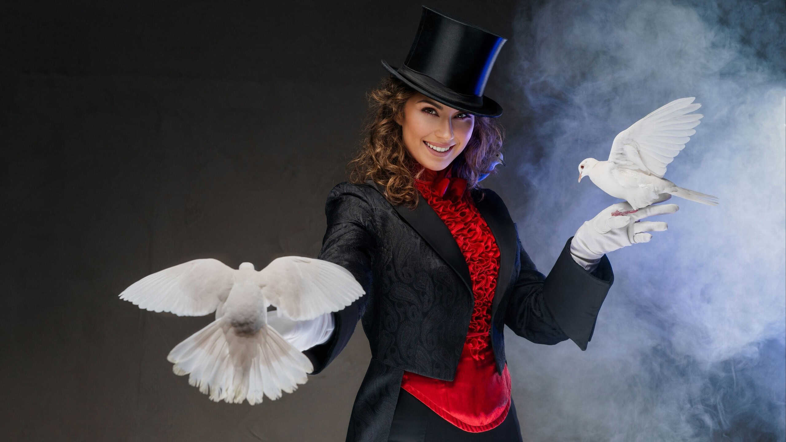 A bewitching moment captured as a woman magician in a magician's costume and black cylinder hat showcases enchanting magic tricks with graceful white doves on a dark, smoky backdrop