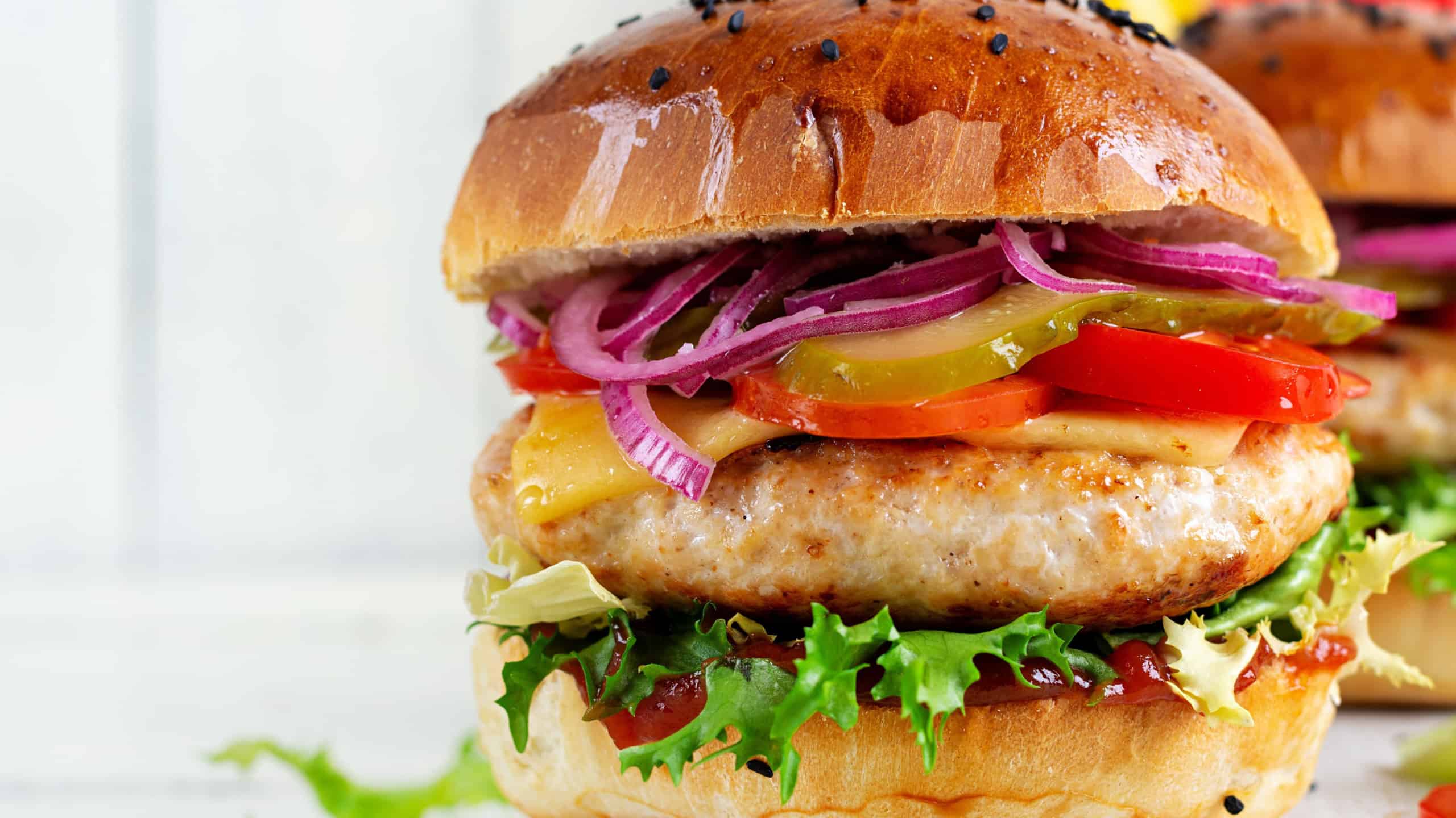 Chicken hamburger. Sandwich with chicken burger, tomatoes, cheese, pickled cucumber and lettuce. Cheeseburger.