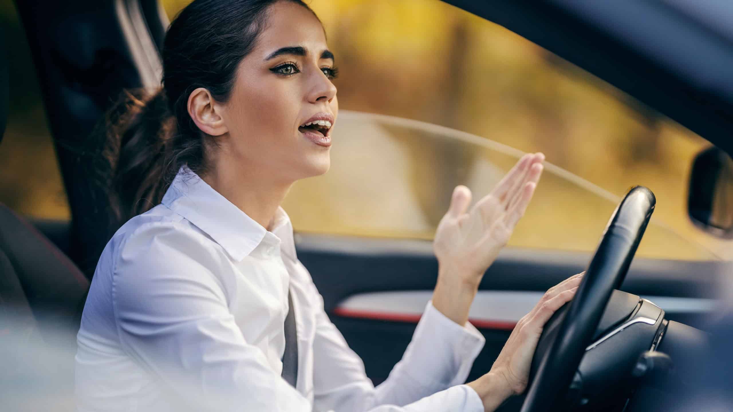 An angry woman is yelling and honking to drivers in traffic jam.