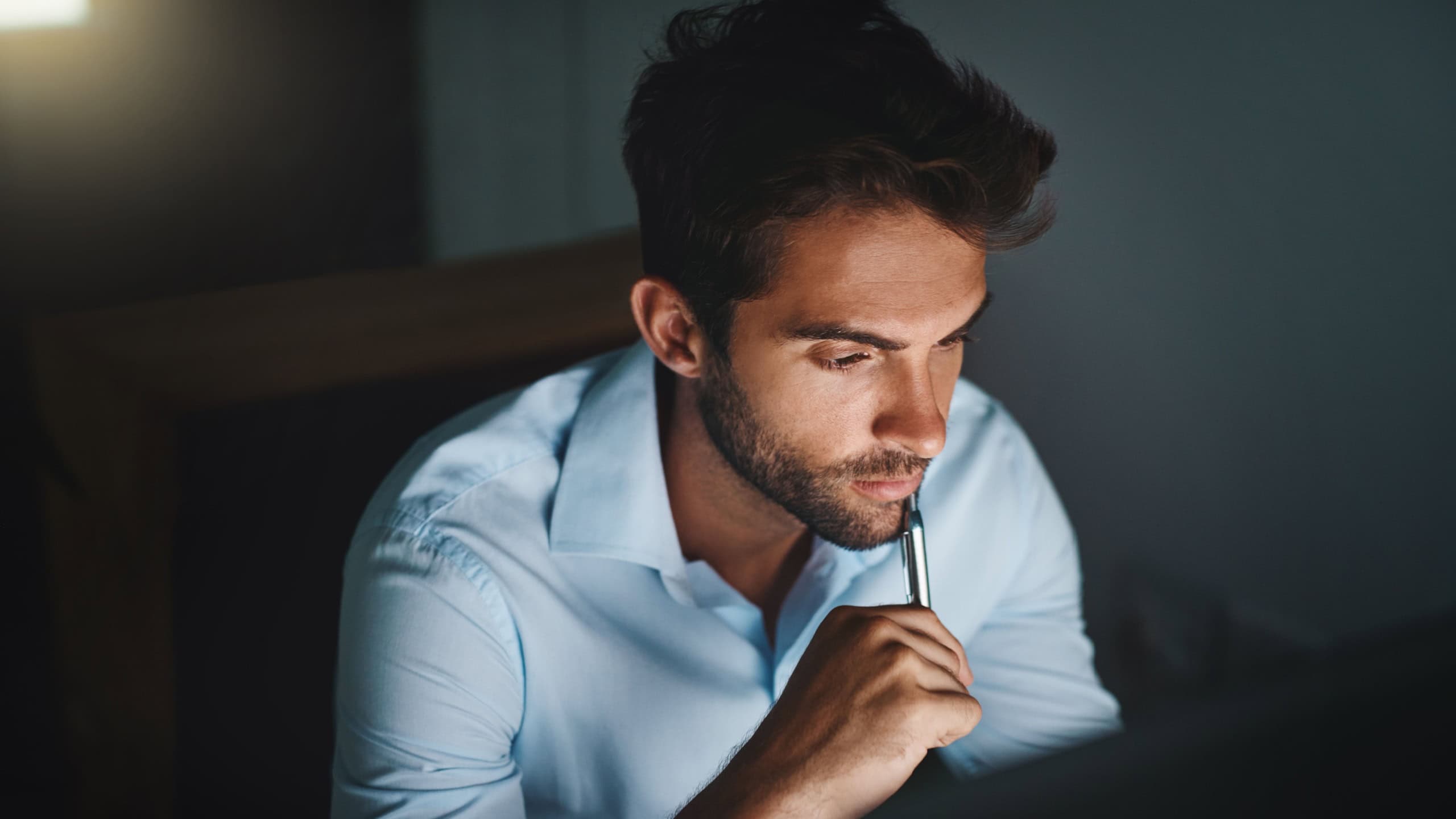 Businessman, thinking and night with computer for decision, choice or planning at office. Young man or employee working late in wonder, reading or online research for project deadline at workplace