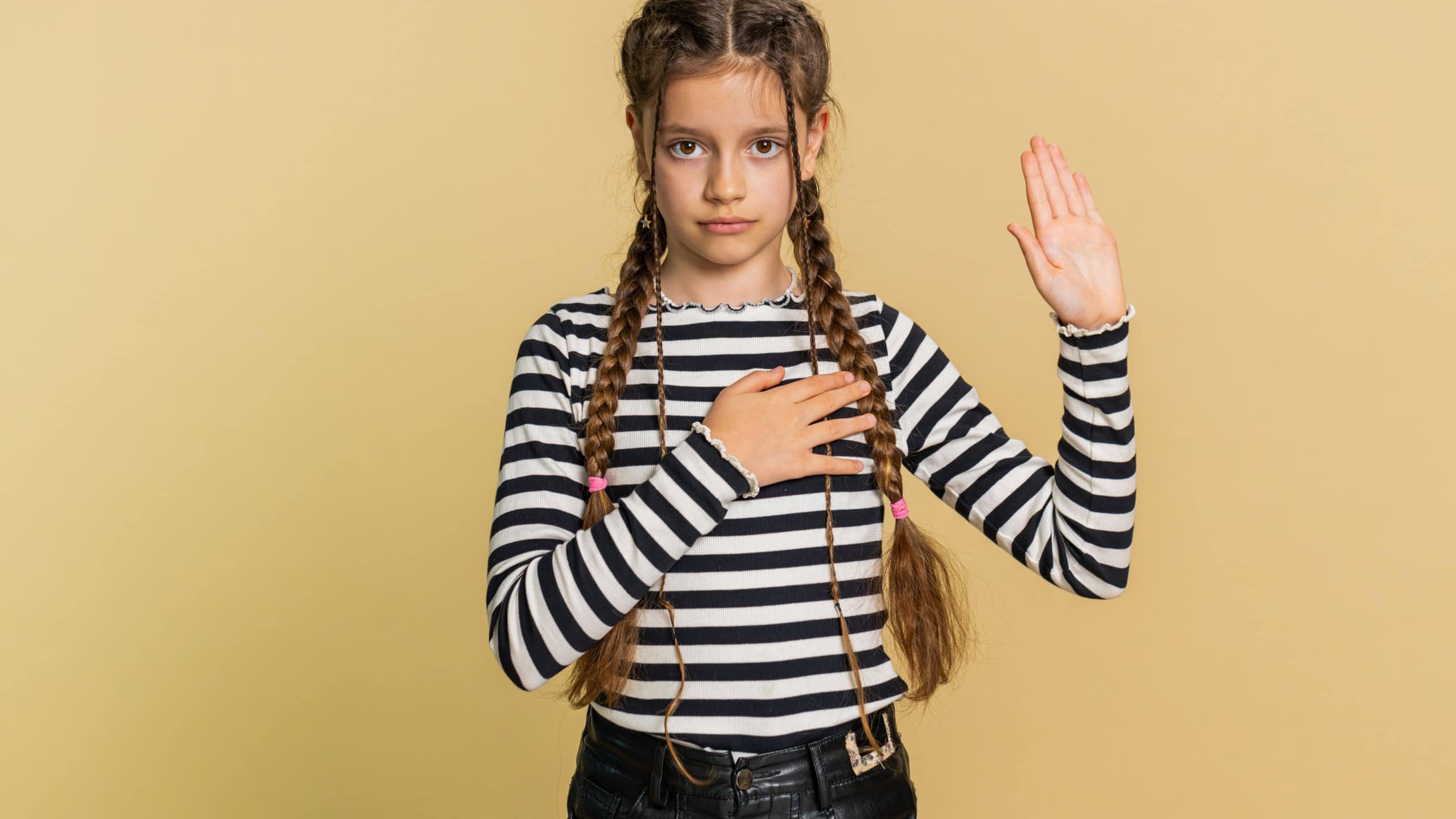 I swear to be honest. Sincere responsible preteen child girl kid raising hand to take oath, promising to be honest, to tell truth, keeping hand on chest, justice. Teenager children on beige background