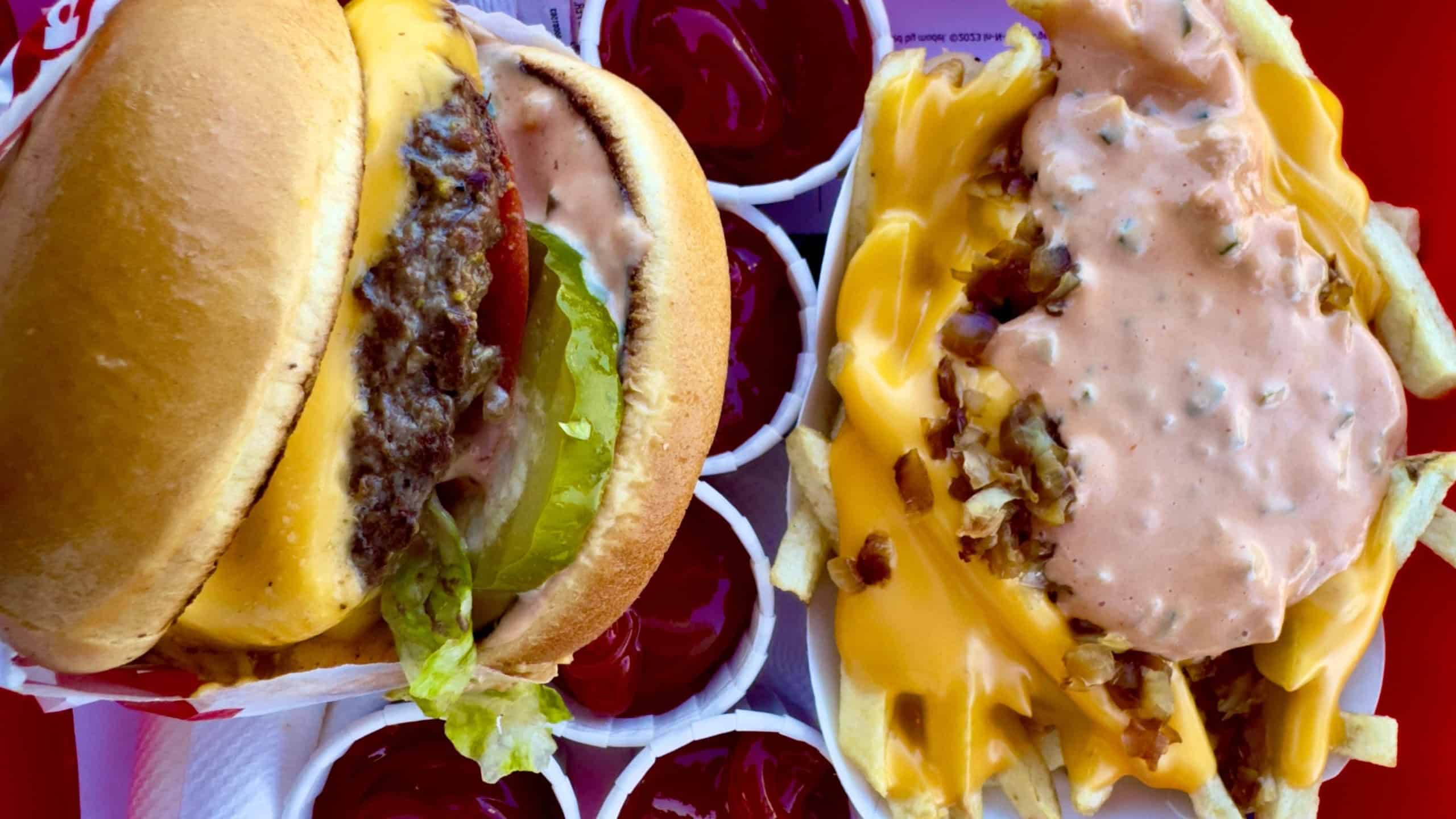 Animal style variations on a double-double hamburger and French fries at In- N-Out Burger fast food restaurant
