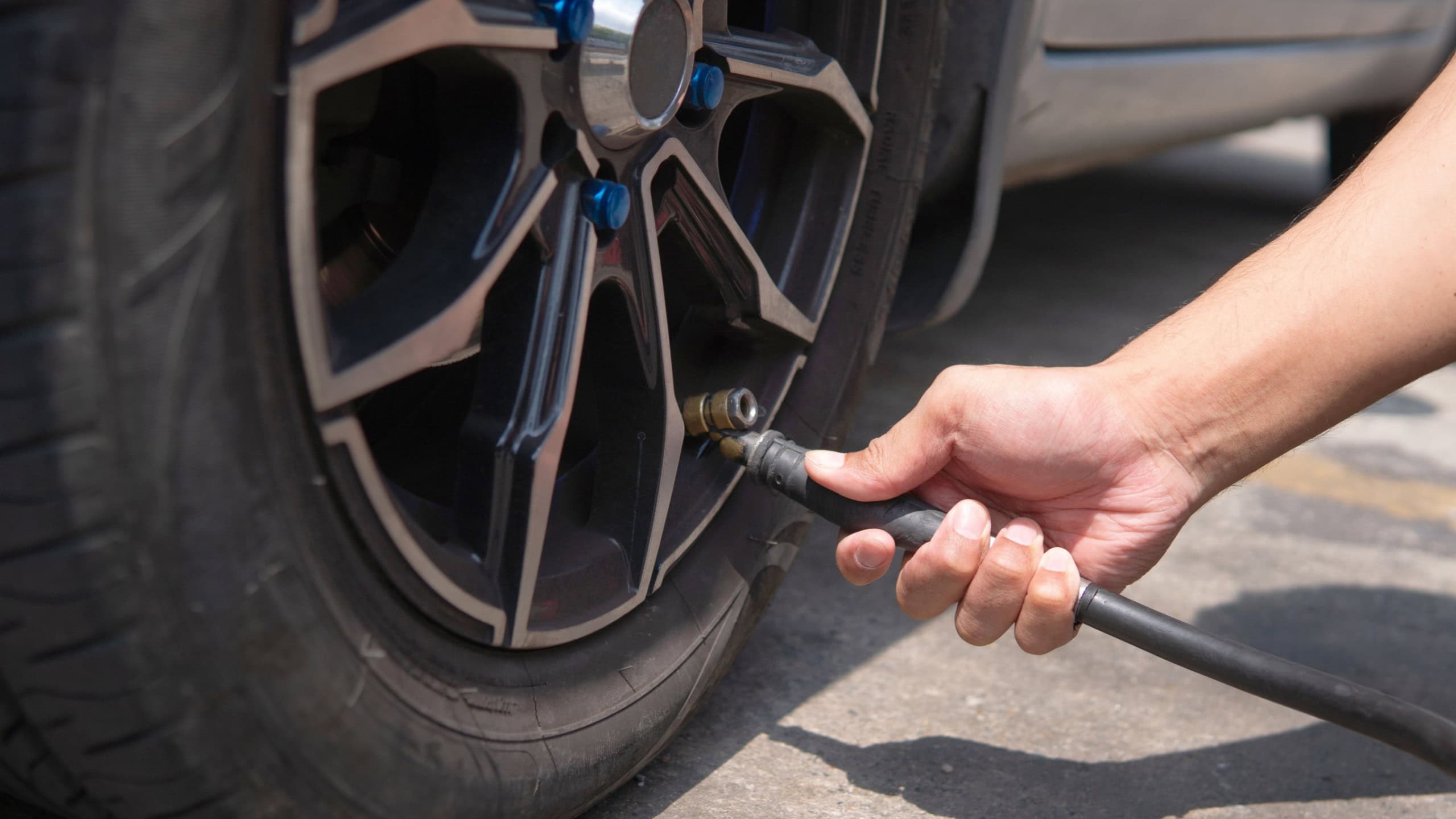 Closeup image of man inflating tire, filling air in the tires of his car.