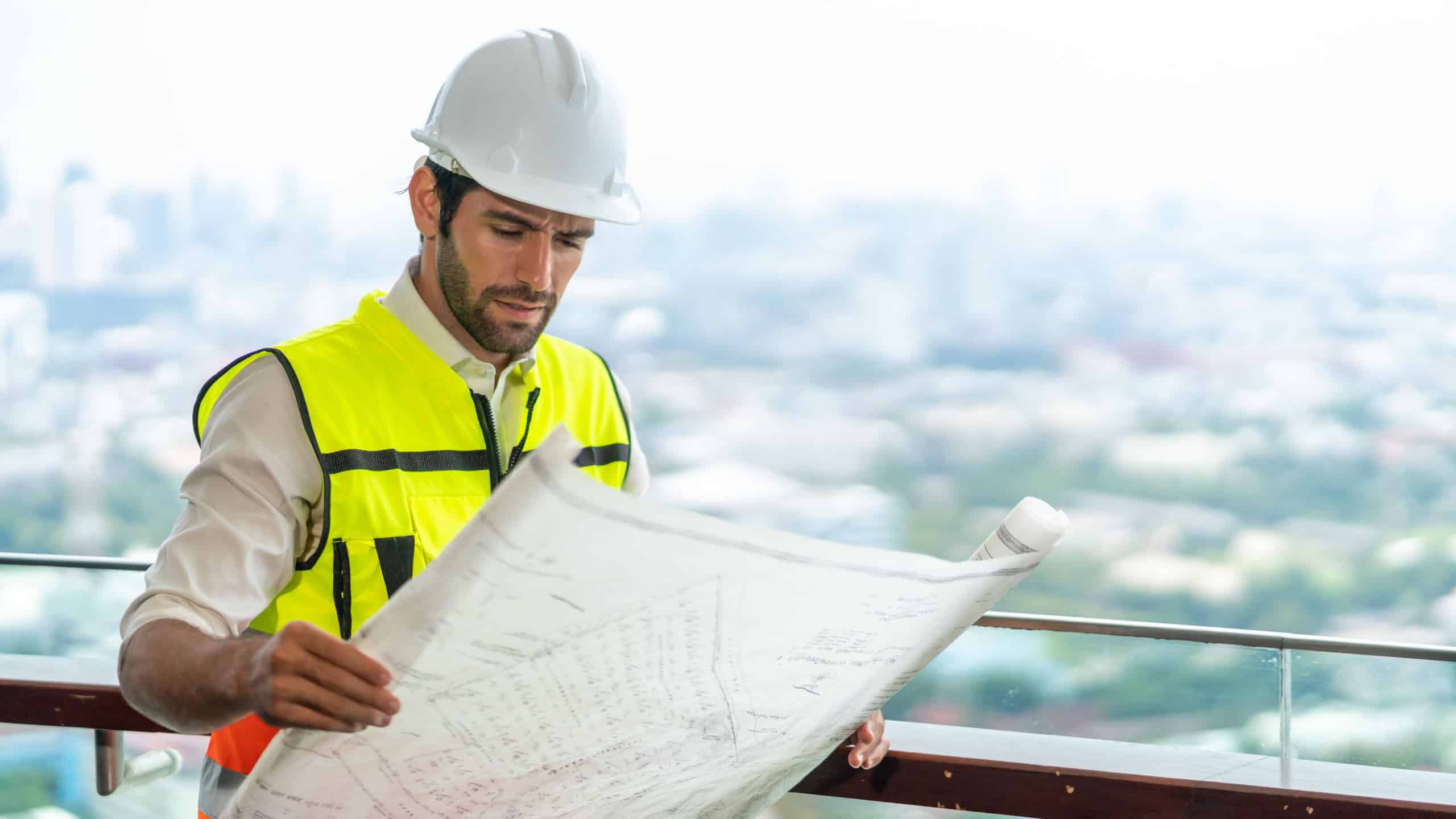 Male civil engineer contractor in safety helmet and jacket standing on construction site building and using mobile phone talking discussion real estate development working plan with architect manager.