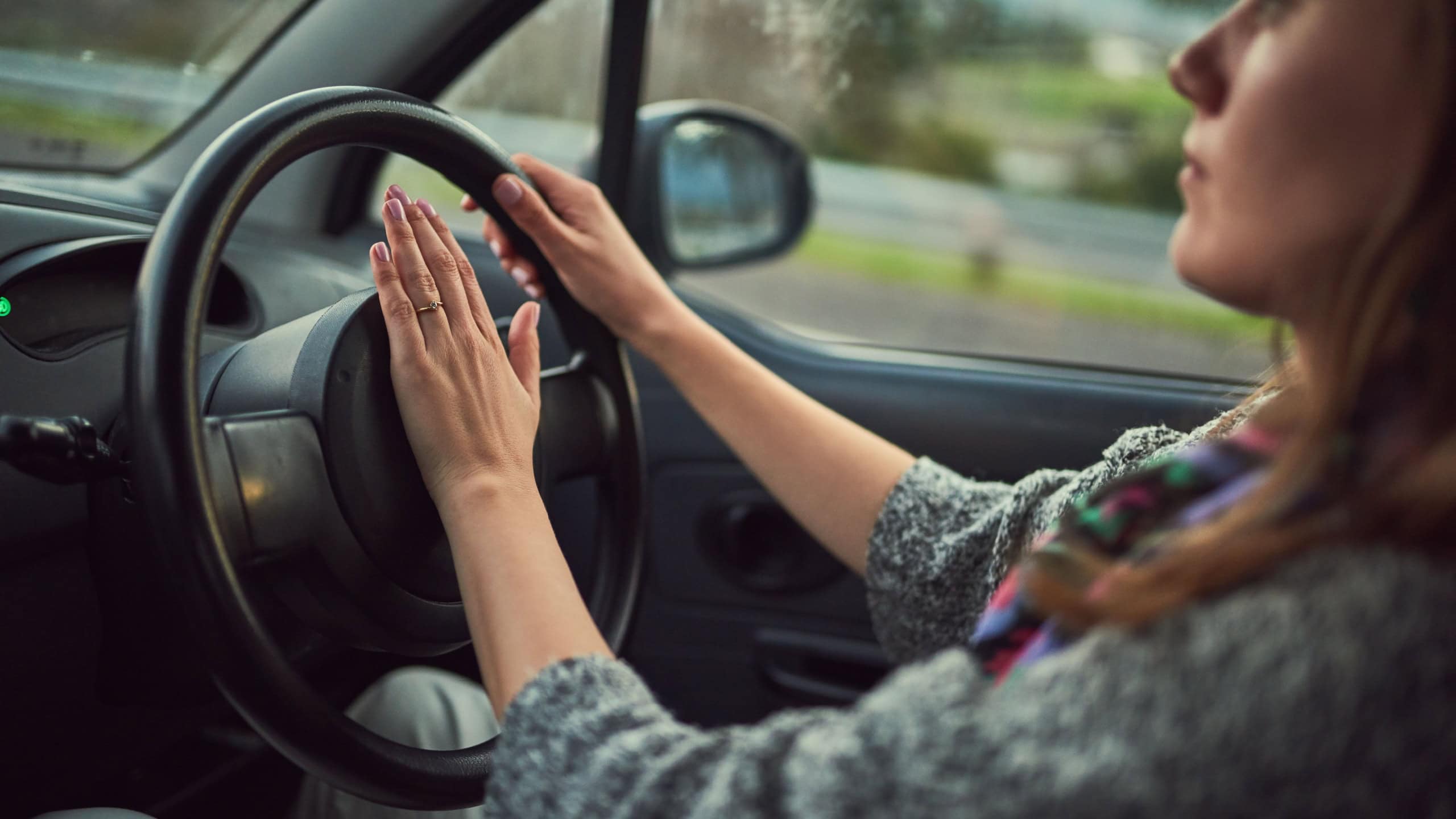 Woman, car and driving with honk on road for alert, emergency or traffic in travel, trip or transport. Female person hooting in vehicle with steering wheel for sound, horn or beep for incoming speed