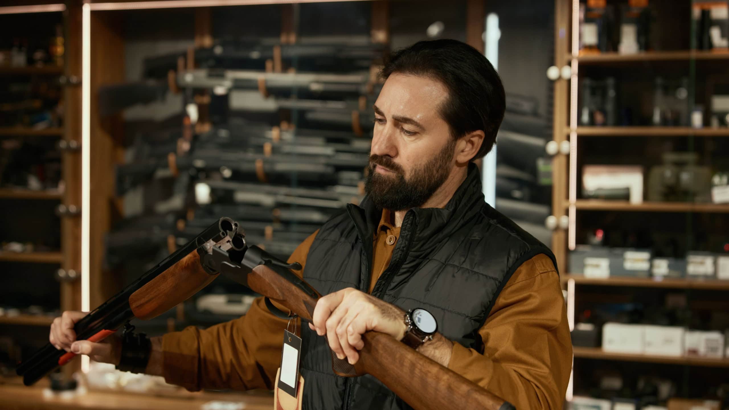 Concentrated salesman checking gun firearm while working at weapon shop