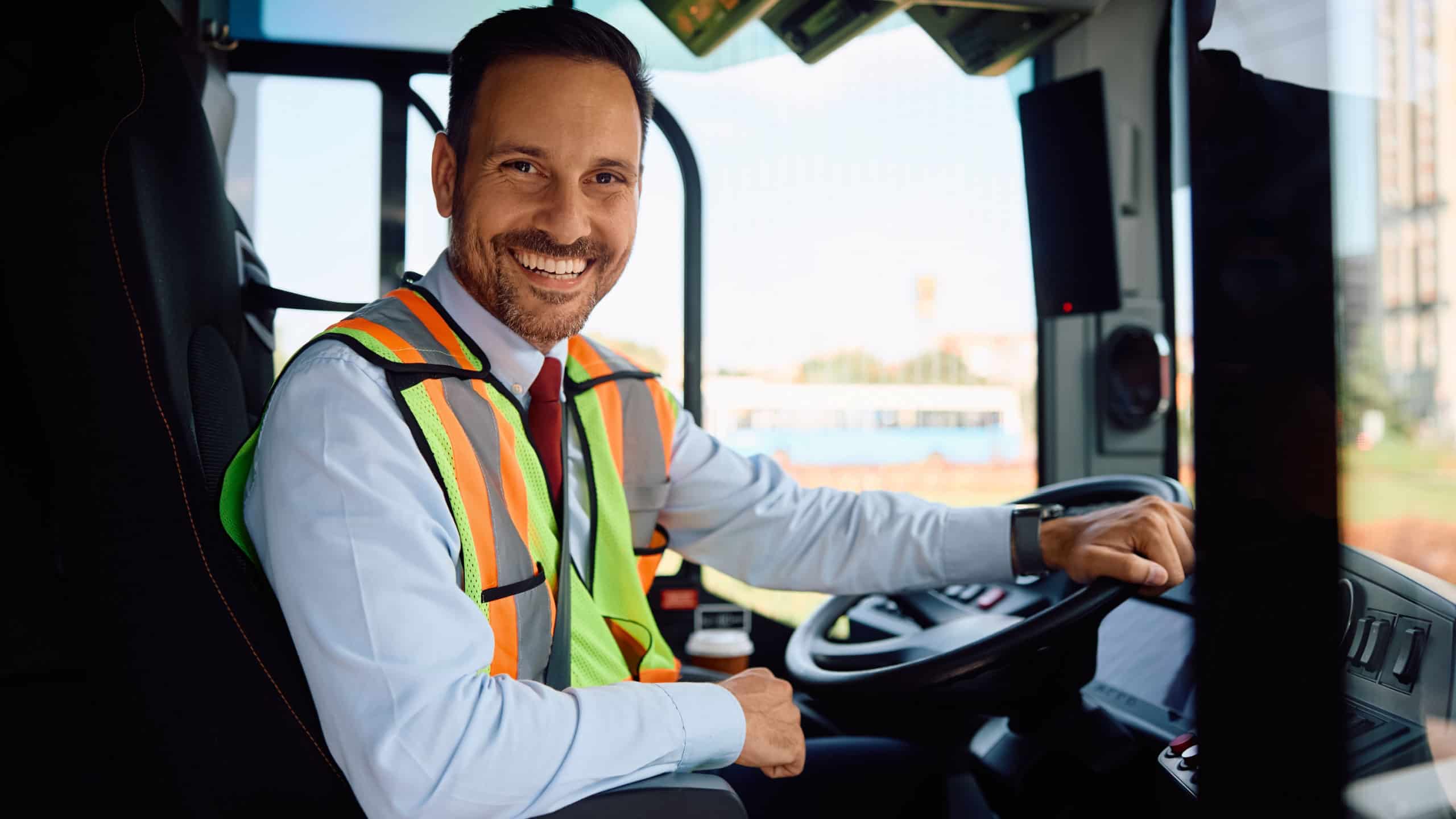 Happy bus driver in vehicle cabin looking at camera.
