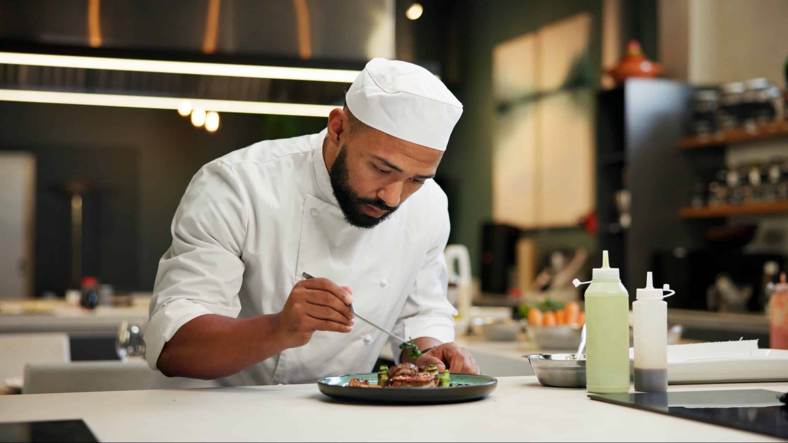 Man, chef and serious with food in kitchen at restaurant for fine dining, meal and creativity. Male employee, professional and cooker with pride for culinarily, hospitality and catering service