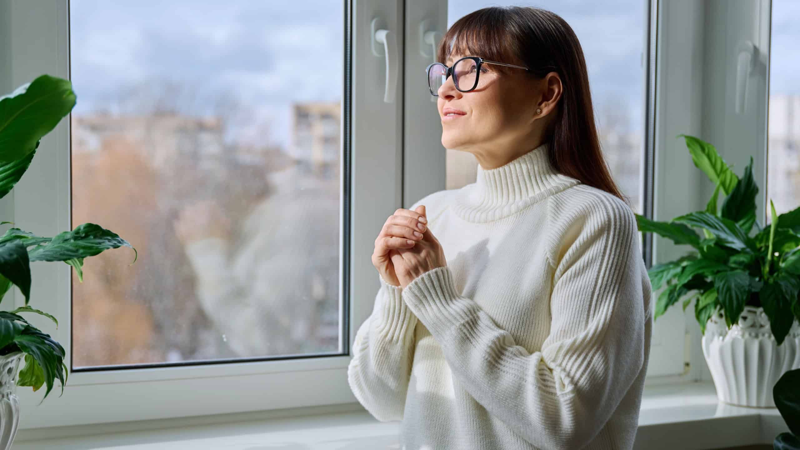 Beautiful happy middle aged woman looking out the window