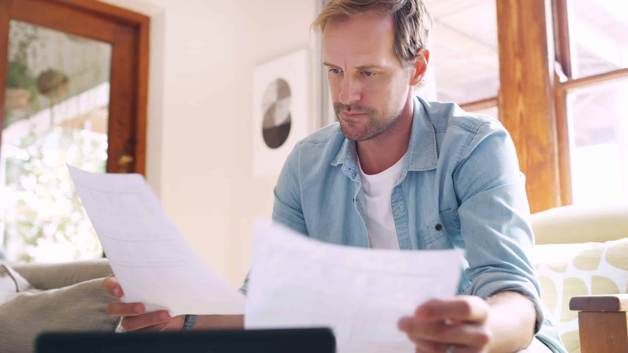 Man, thinking and relax with documents at house for tablet, financial bankruptcy or payment debt of mortgage. Person, reading and paperwork for budget crisis, eviction letter and investment solution