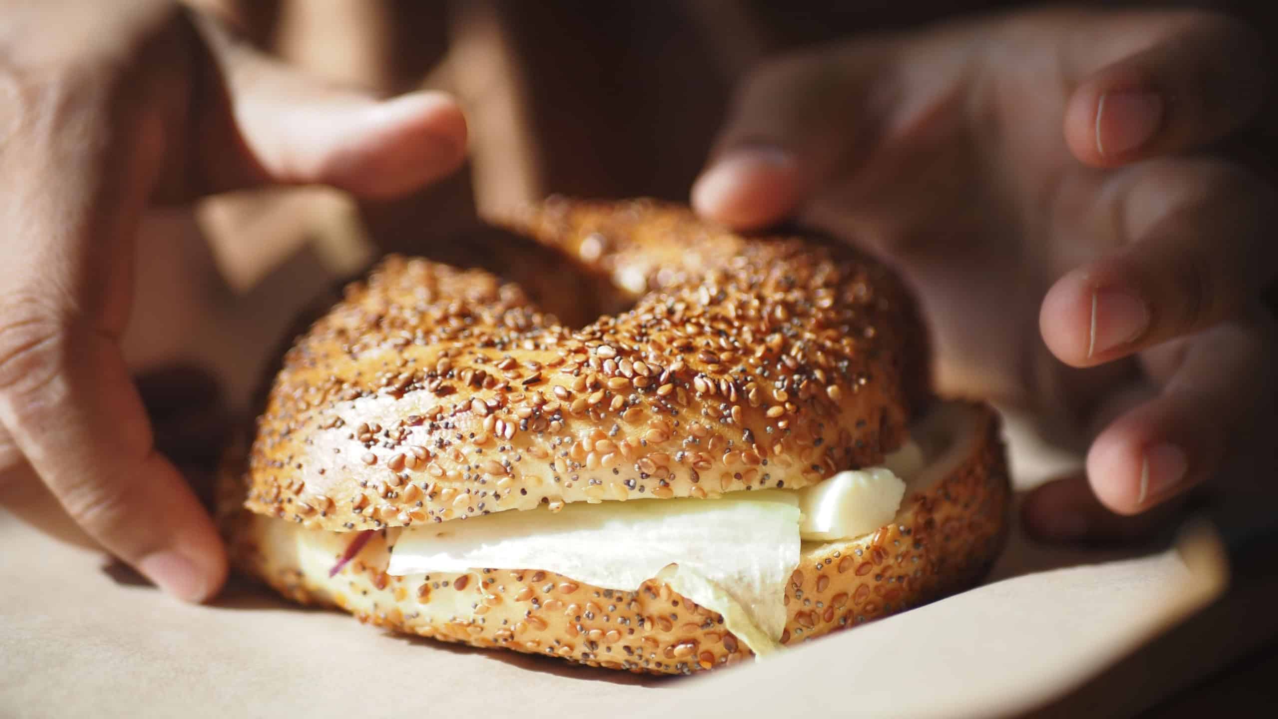 Enjoy a Freshly Made Sesame Bagel with Cream Cheese on a Wooden Board, perfect for any meal