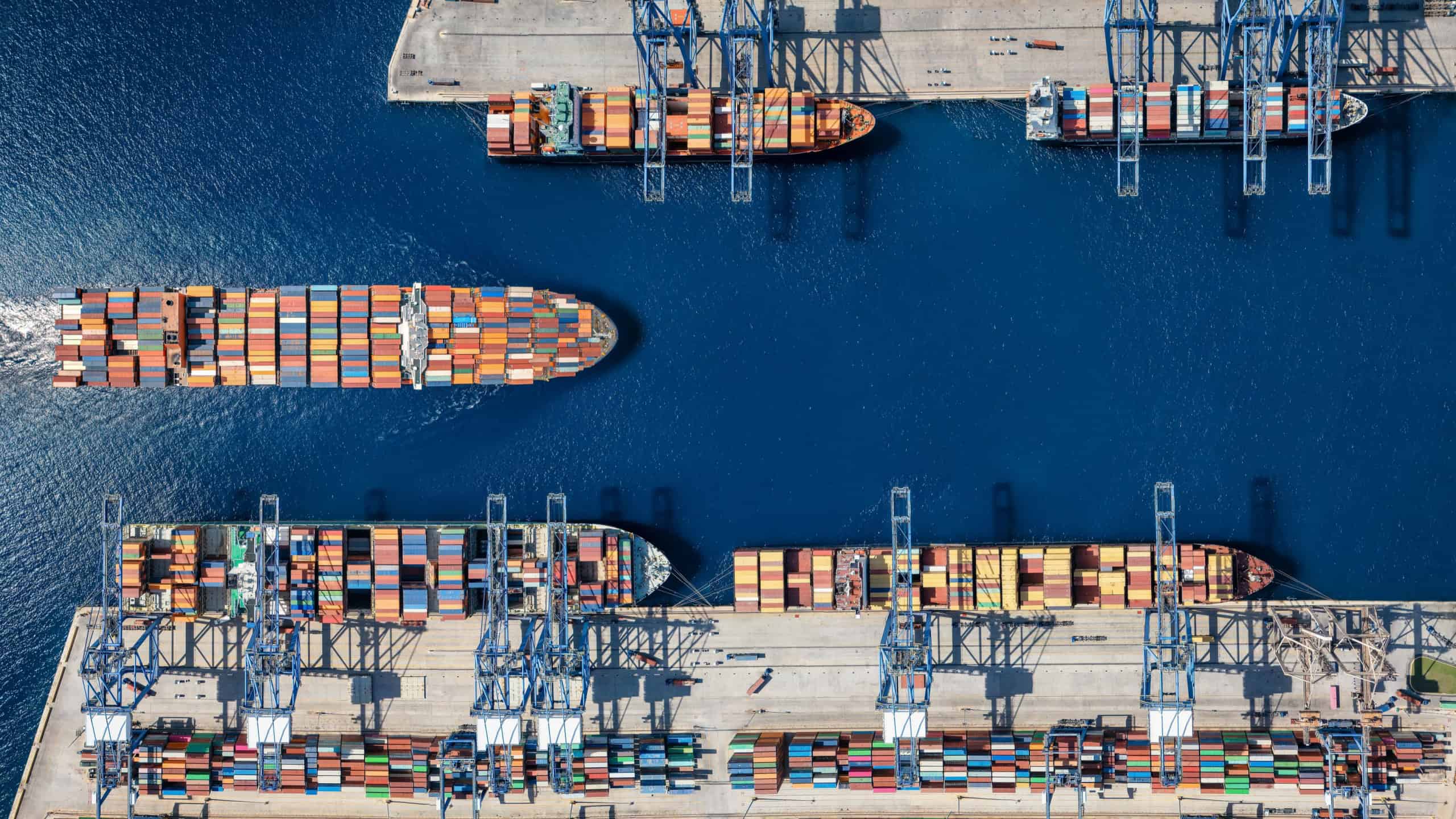 Aerial top down view of a large container cargo ship terminal harbor with loading activity and vessel traffic