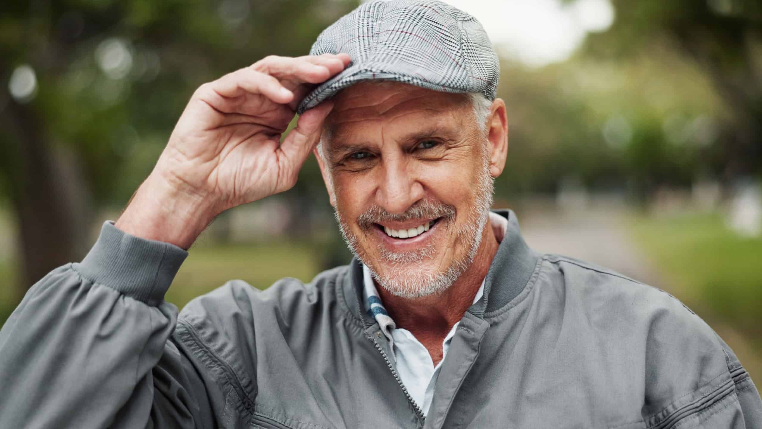 Elderly man, portrait and hat with park for welcome, greeting and polite manners with smile. Senior person, happy and outdoor for hello with tipping cap, friendly attitude and retirement in Australia