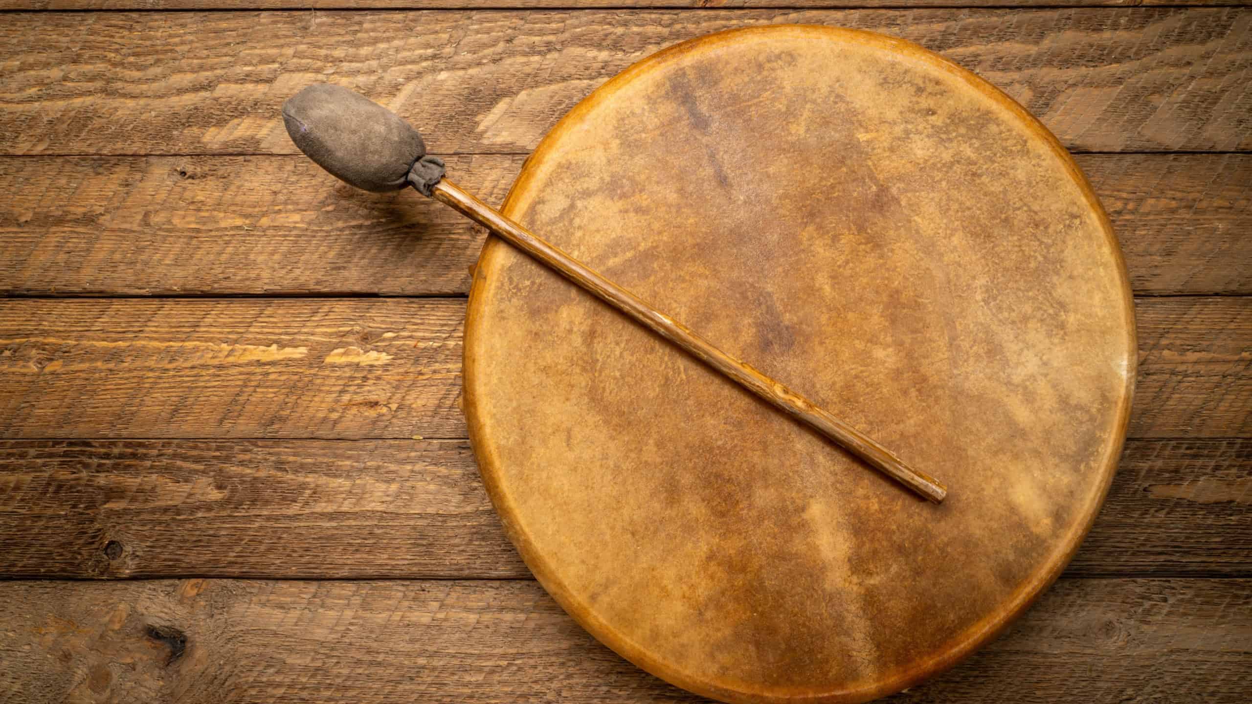 Handmade, native American style, shaman frame drum covered by goat skin with a beater on a rustic wood