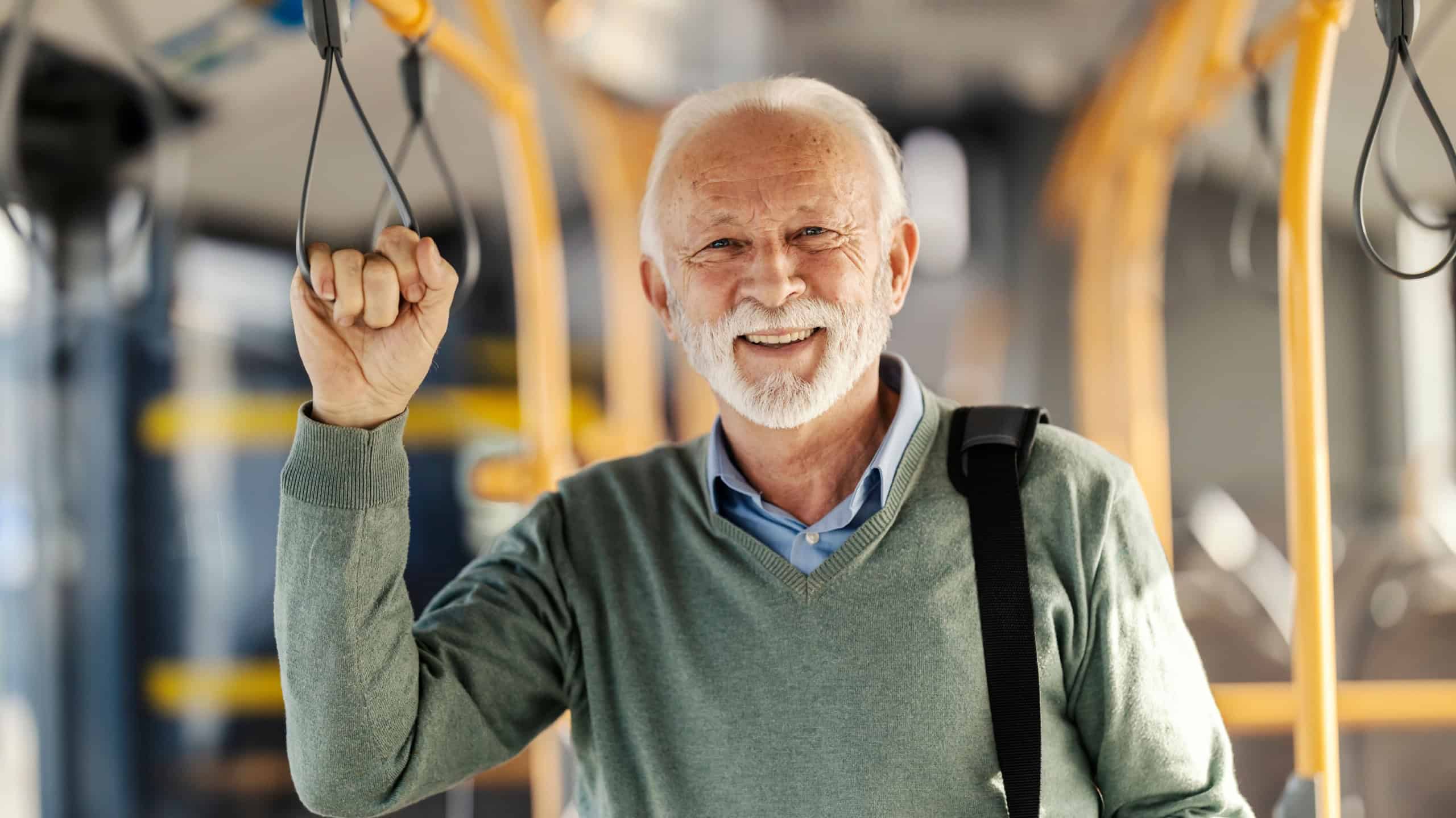Portrait of happy senior passenger commuting by public transportation and smiling at the camera.