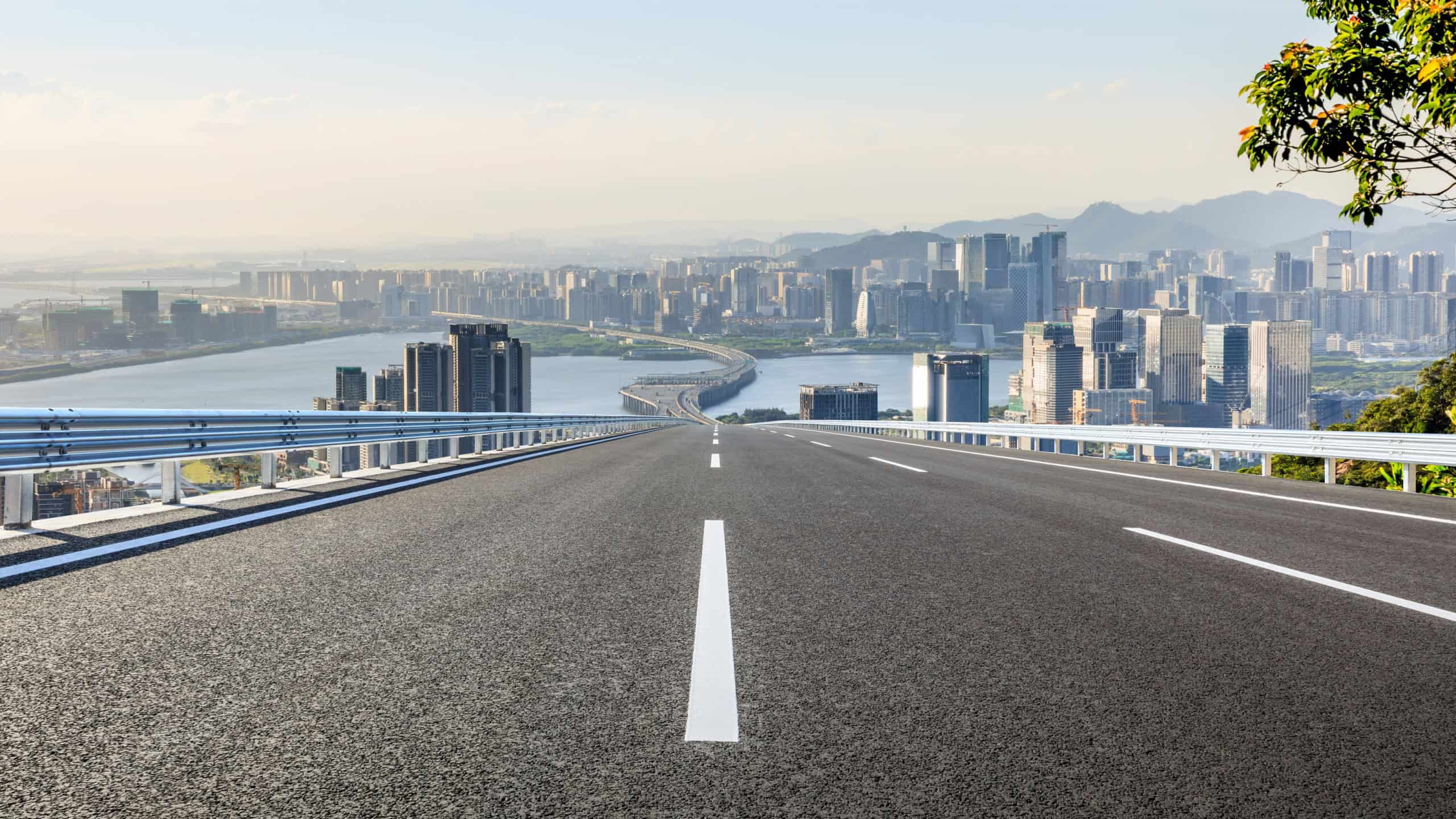 A long road leads to the urban skyline and city buildings