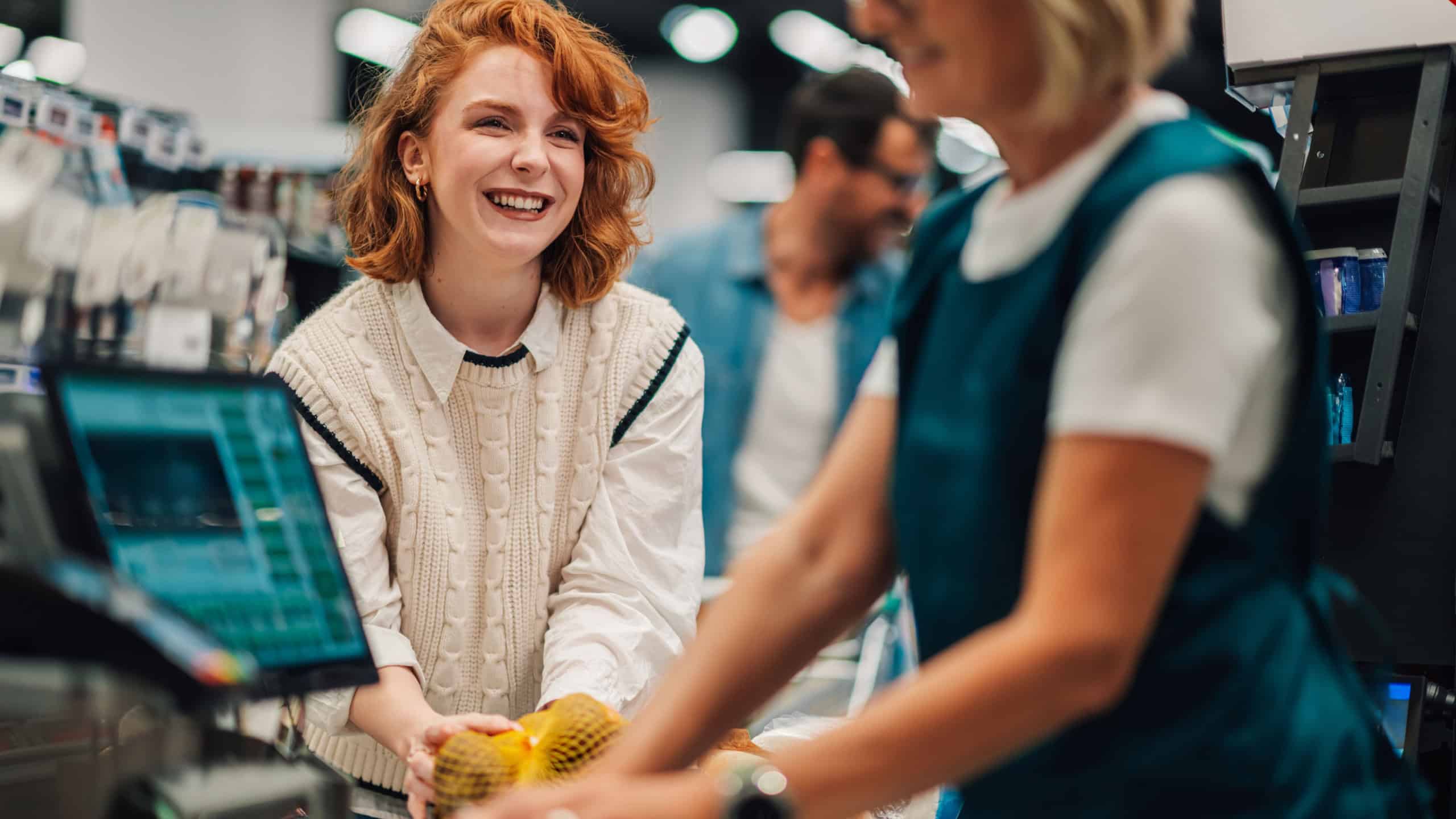 Happy customer smiling at the cashier while scanning groceries at the supermarket checkout, modern and efficient shopping experience