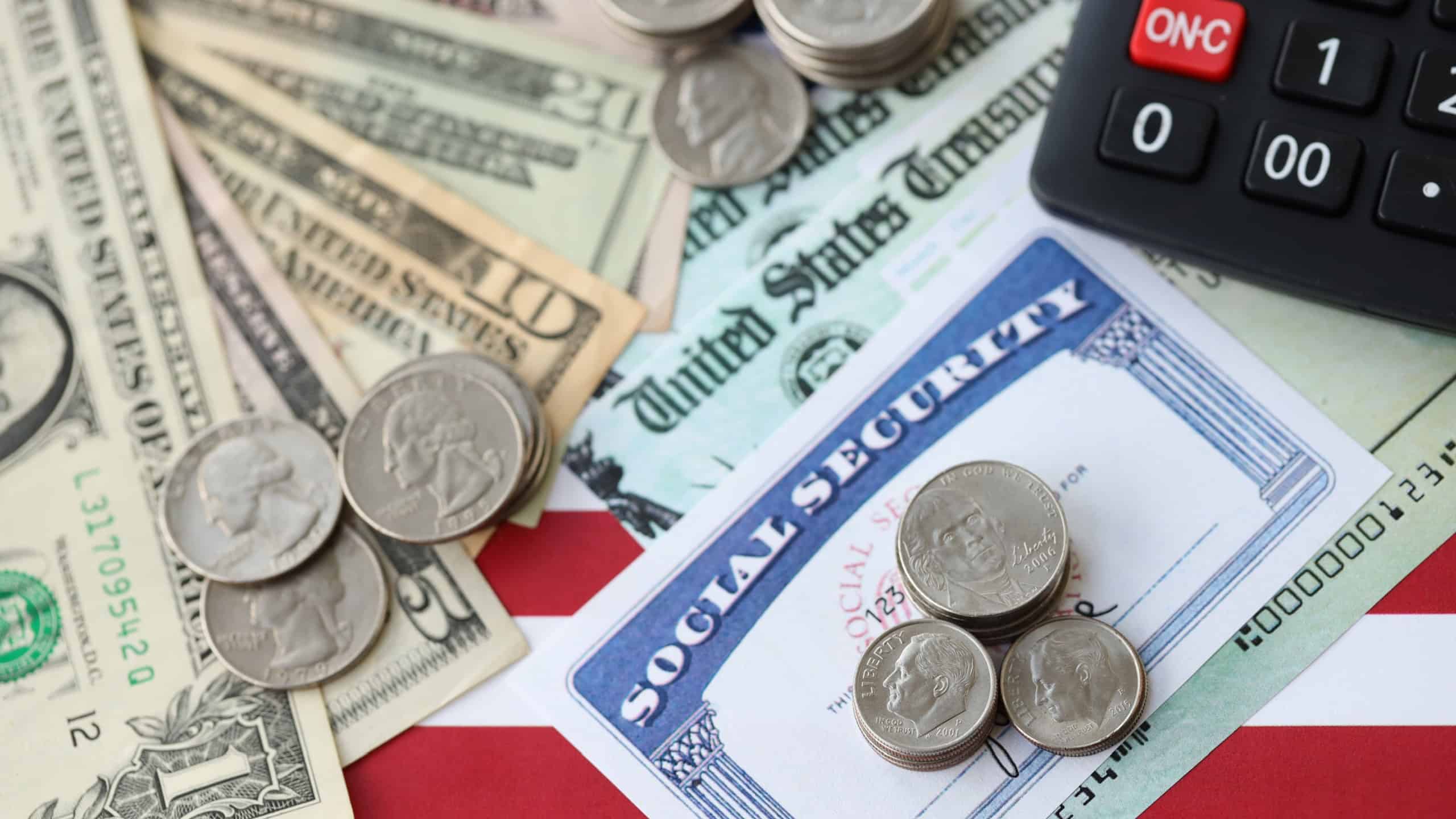 American US dollars money bills, social security number card and calculator on American flag