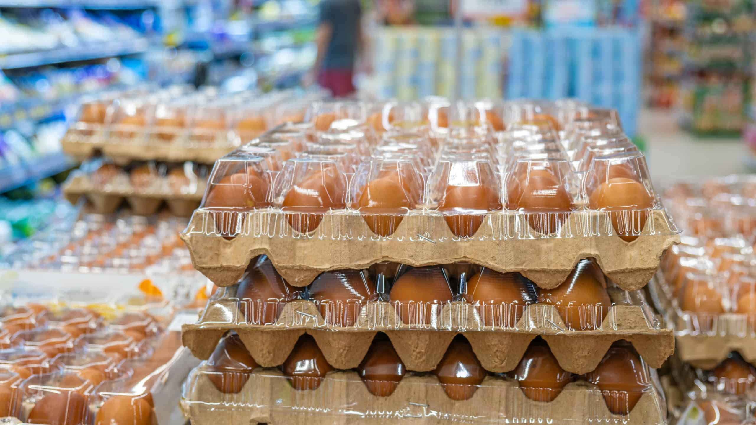 Brown eggs stacked in cardboard and plastic trays on display in supermarket aisle. Grocery shopping, fresh food supply, retail presentation, and food packaging