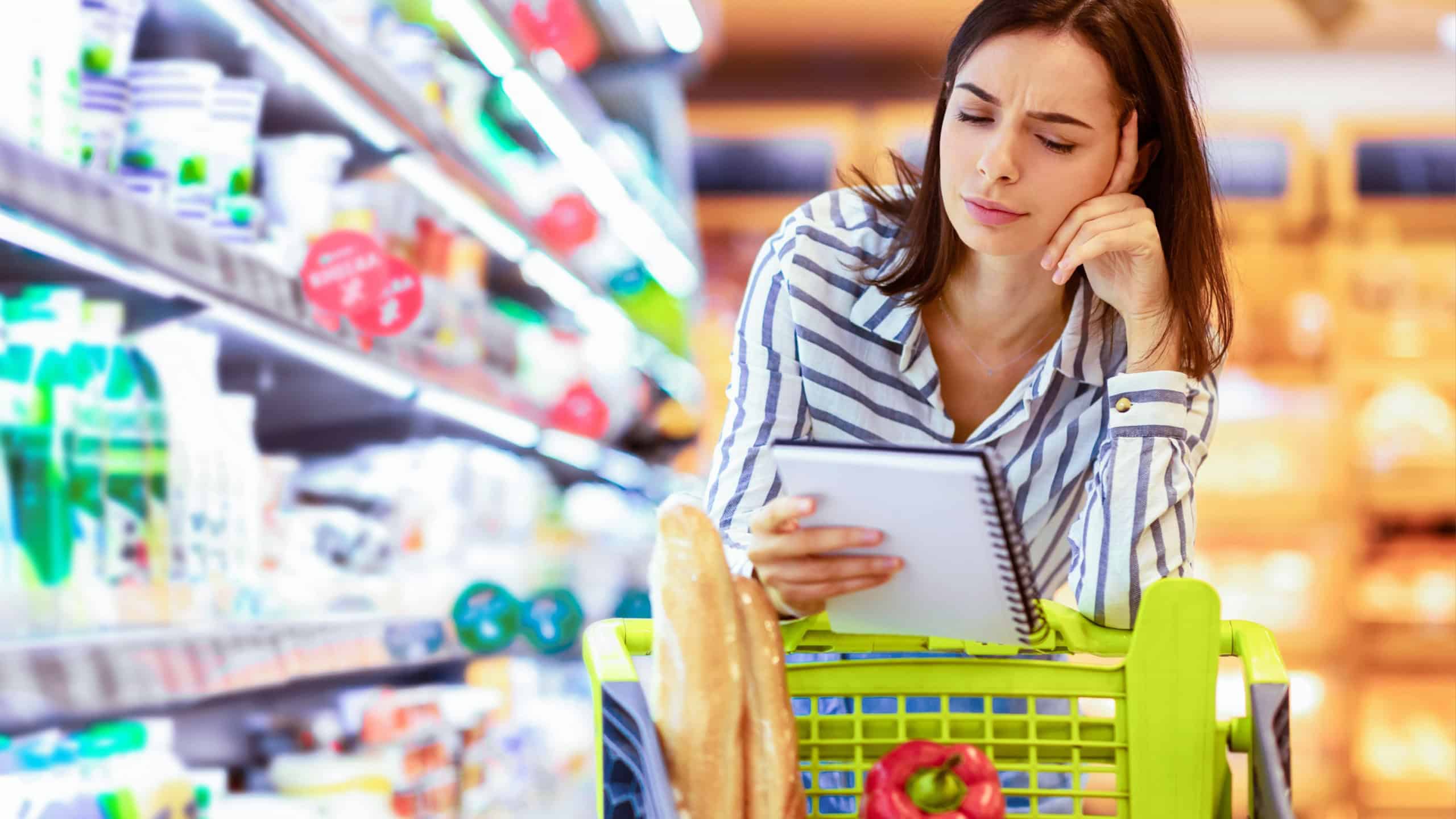 Young woman with shopping list in supermarket