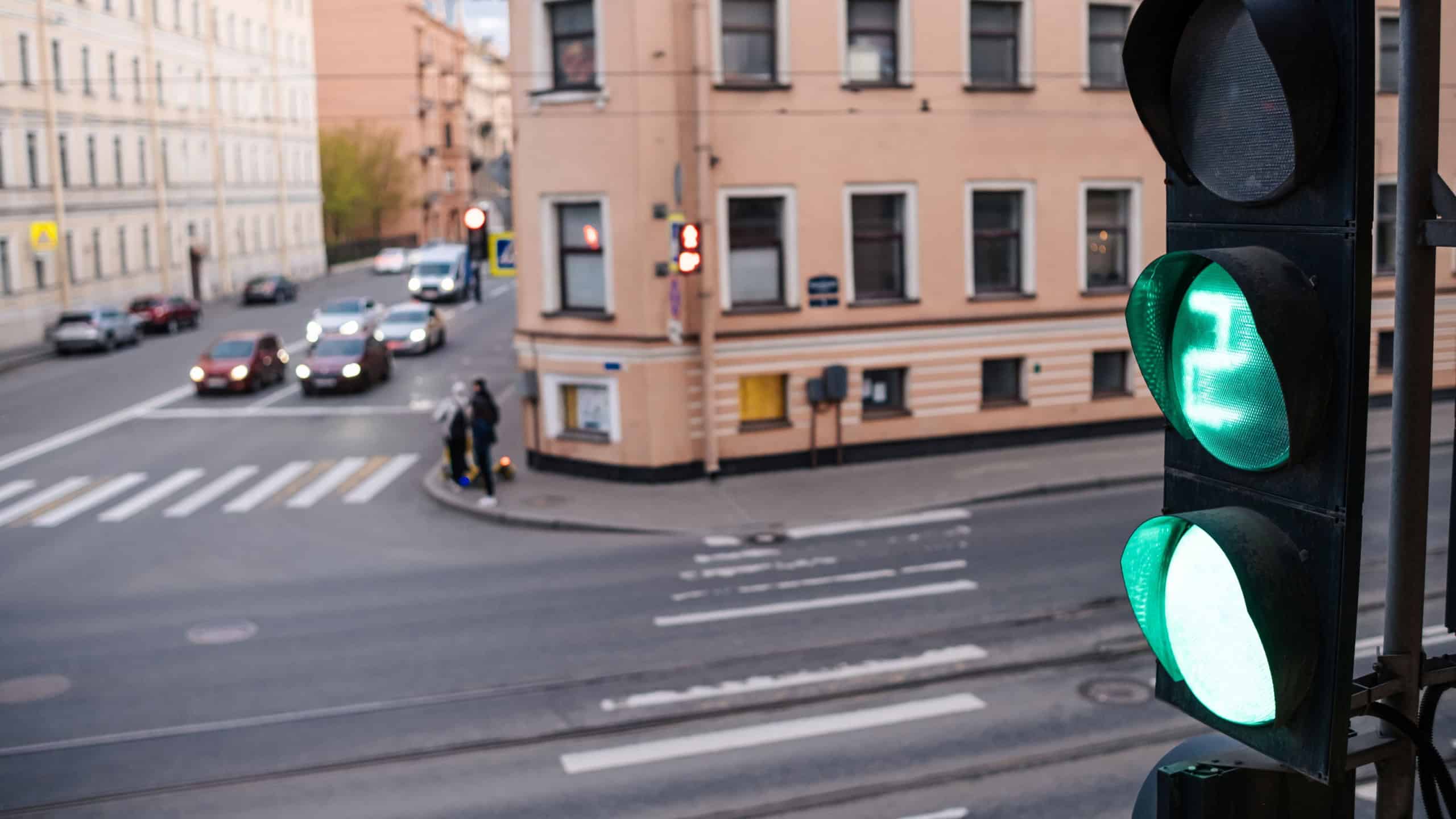 Green traffic light signals safe passage for vehicles and pedestrians at a busy urban intersection during the afternoon, ensuring smooth movement.