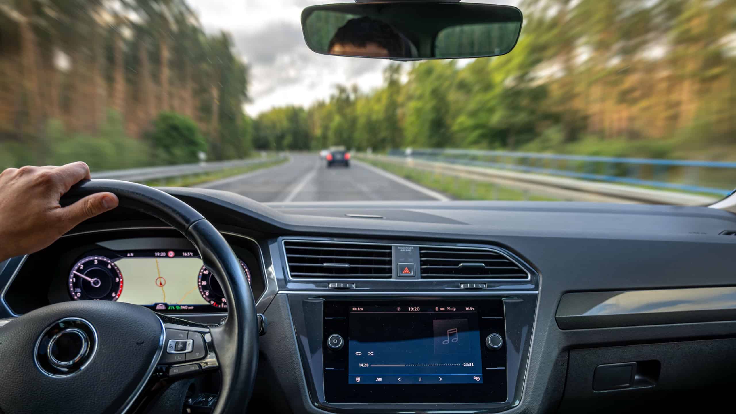 Driver's hand on wheel. Forest road. Speed and blur effect.
