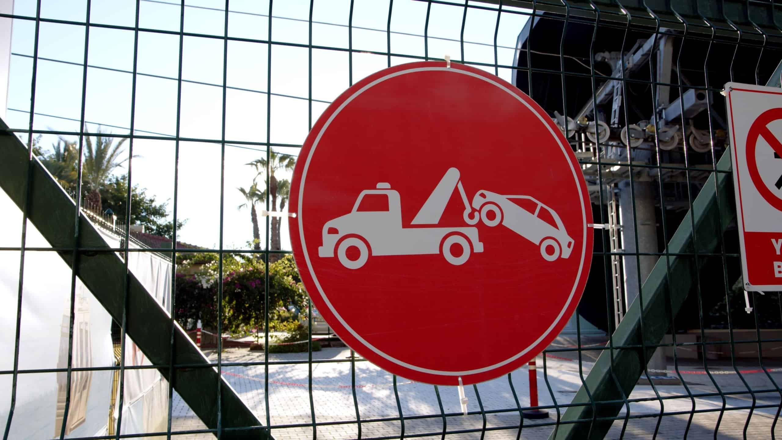 Warning sign prohibits unauthorized parking in a busy area near shops and restaurants