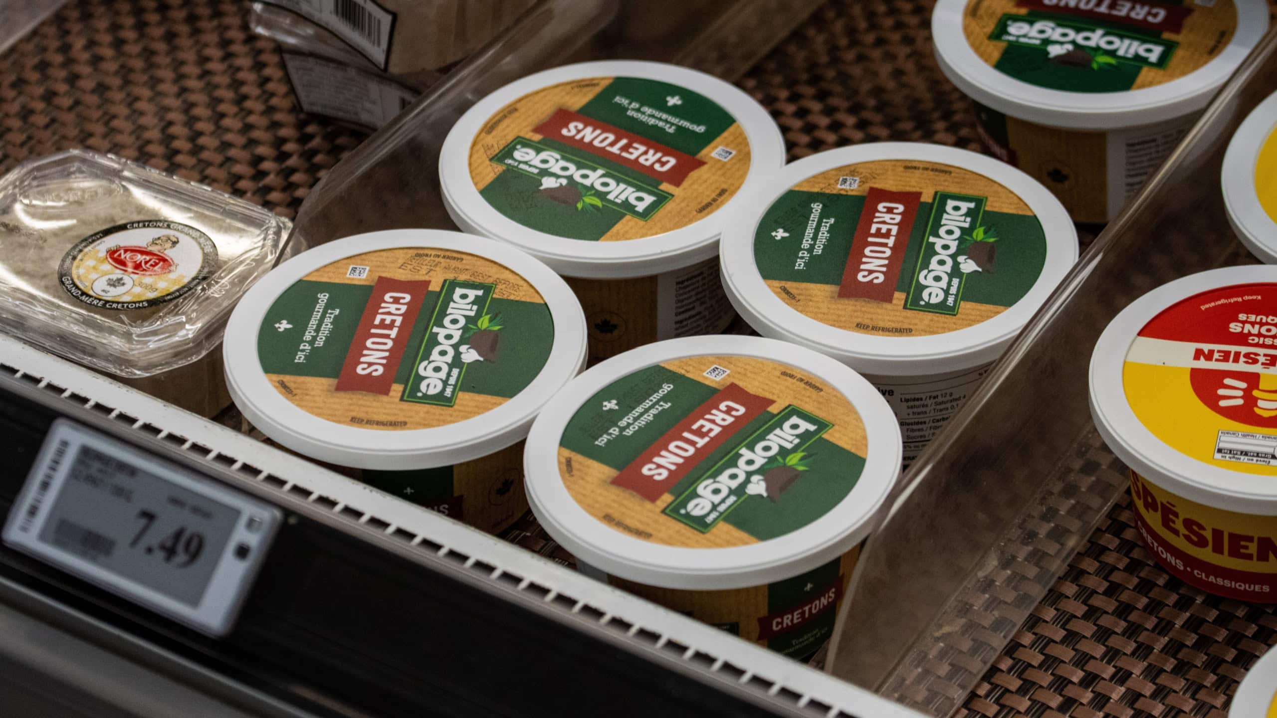 Assorted supermarket cretons containers displayed inside refrigerated section with price tag visible