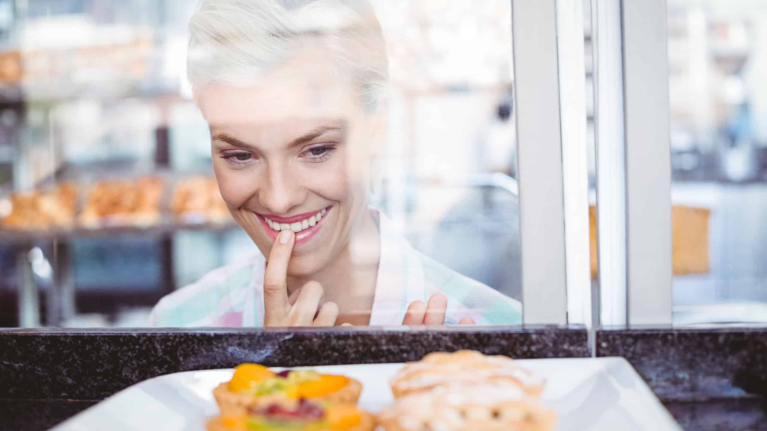 Hesitating pretty woman looking at fruit pie at the bakery