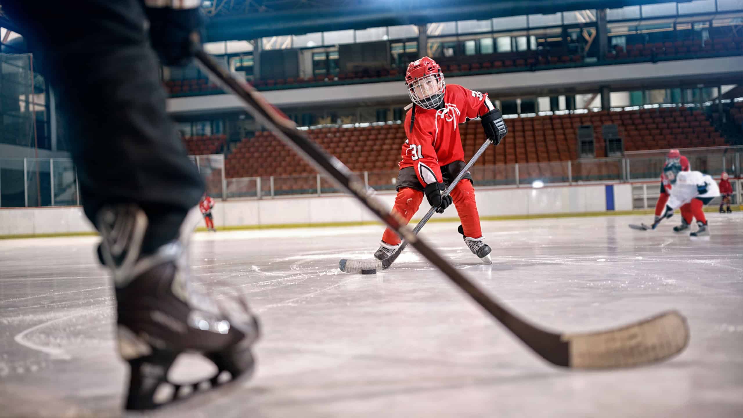 Hockey match at rink player in action kicking on goal