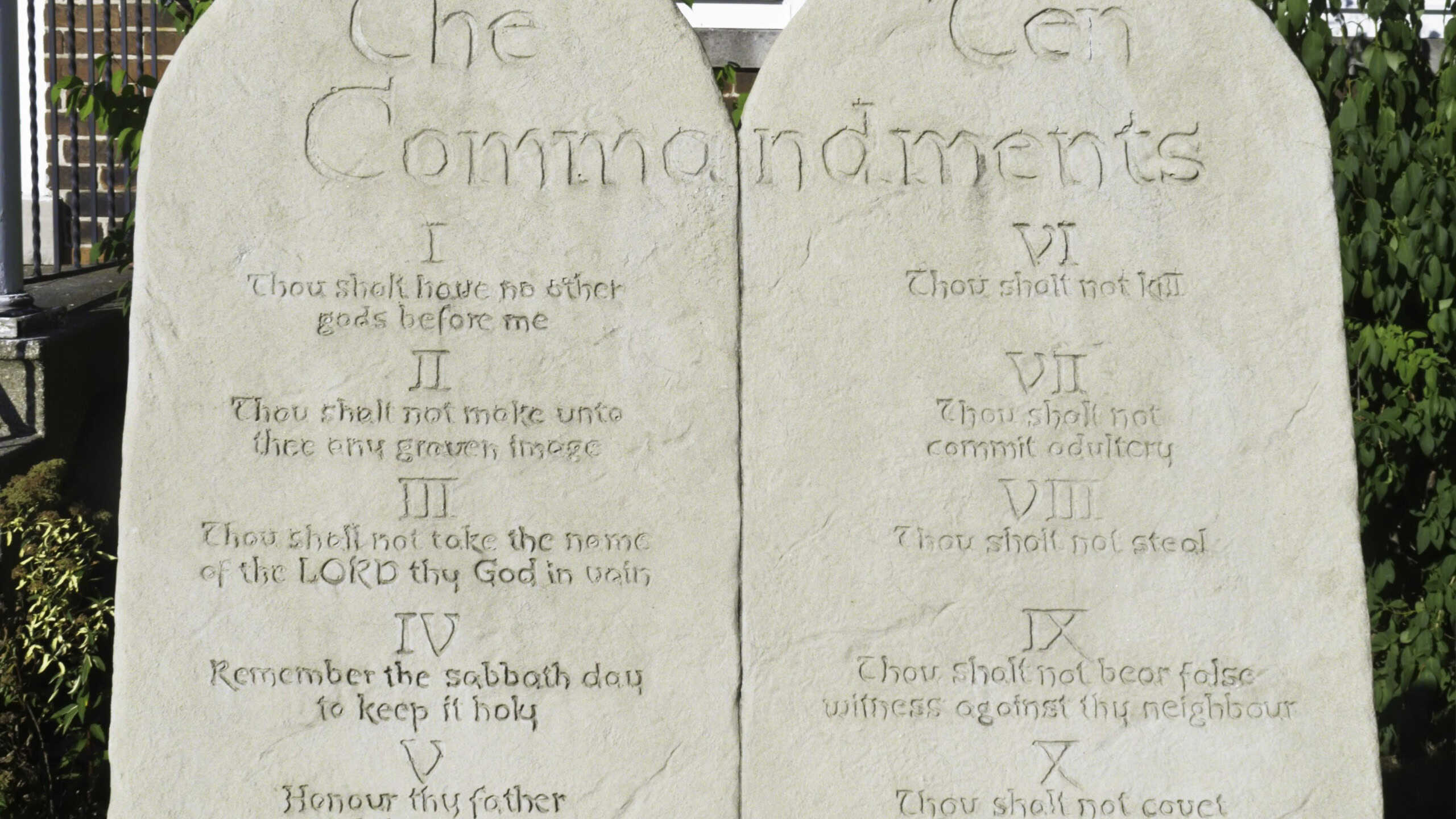 Two stone tablets engraved with the Ten Commandments in front of urban brick church