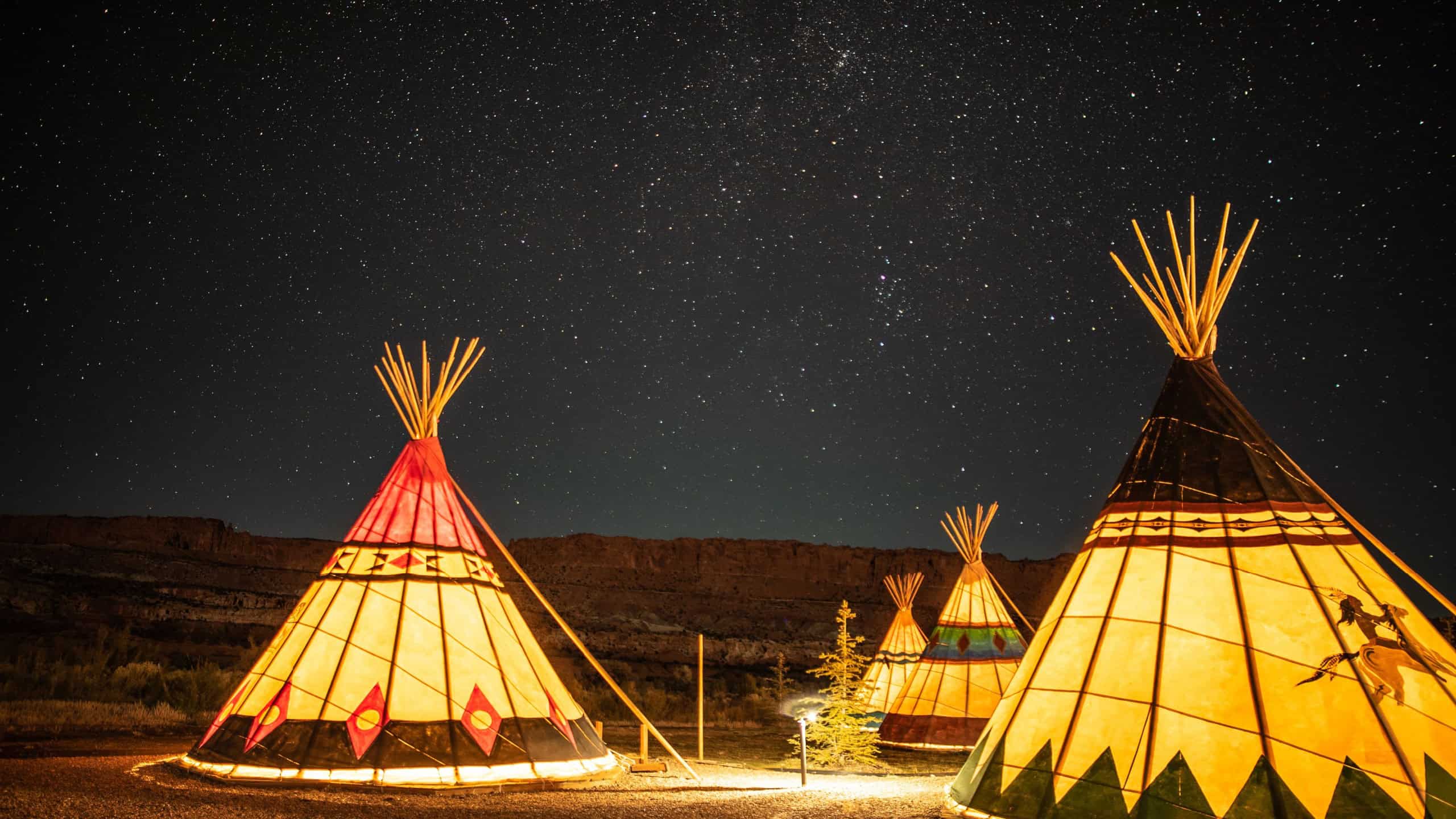 Illuminated Teepees under glowing night sky