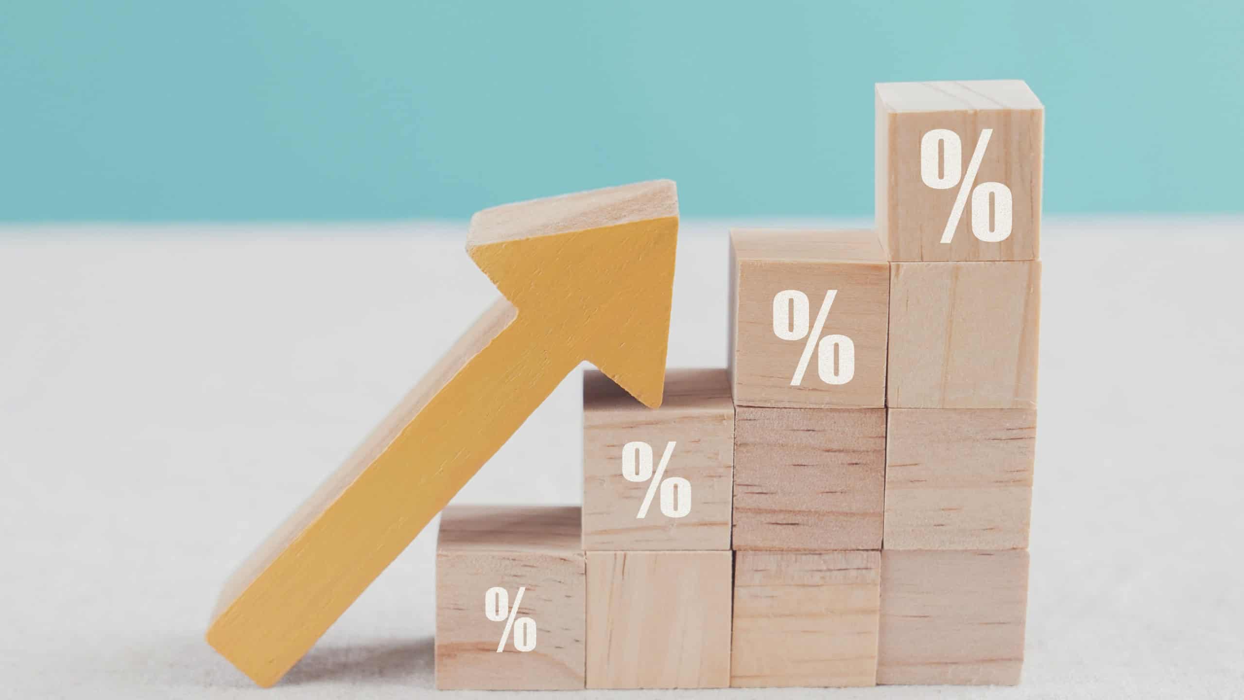 Wooden blocks with percentage sign and arrow up, financial growth, interest rate increase, inflation, high price and tax rise concept