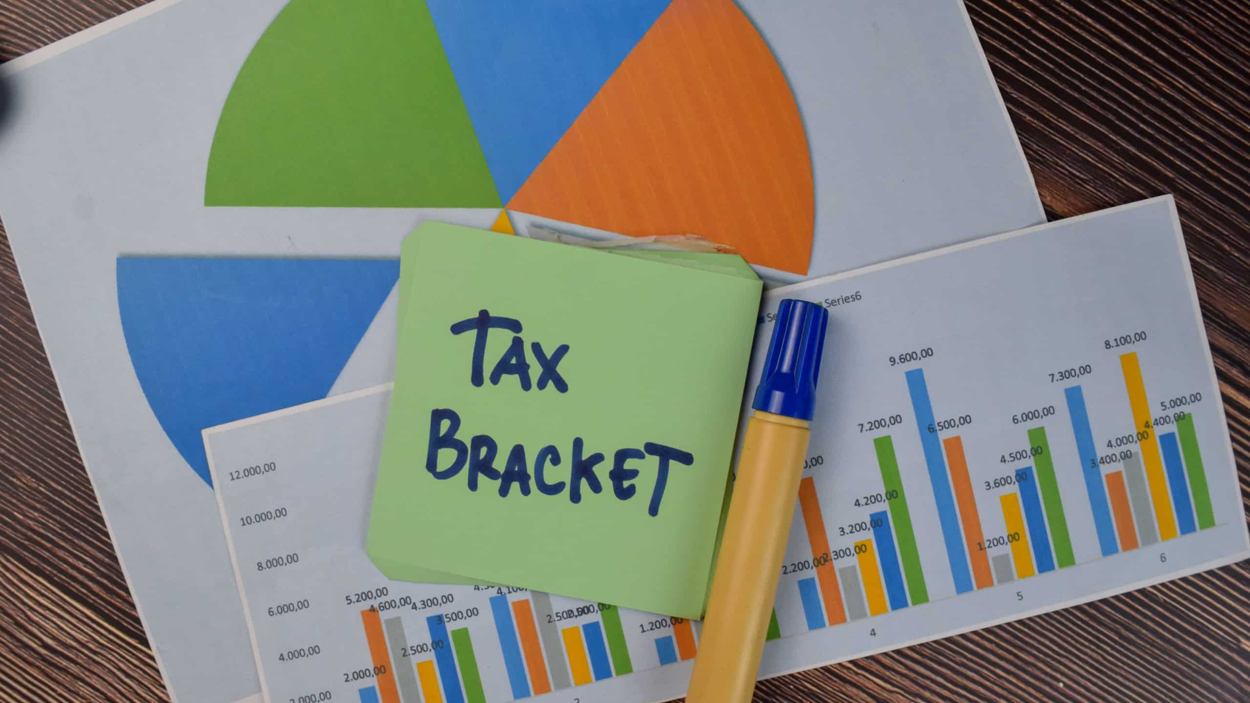 Tax Bracket write on sticky notes isolated on Wooden Table.