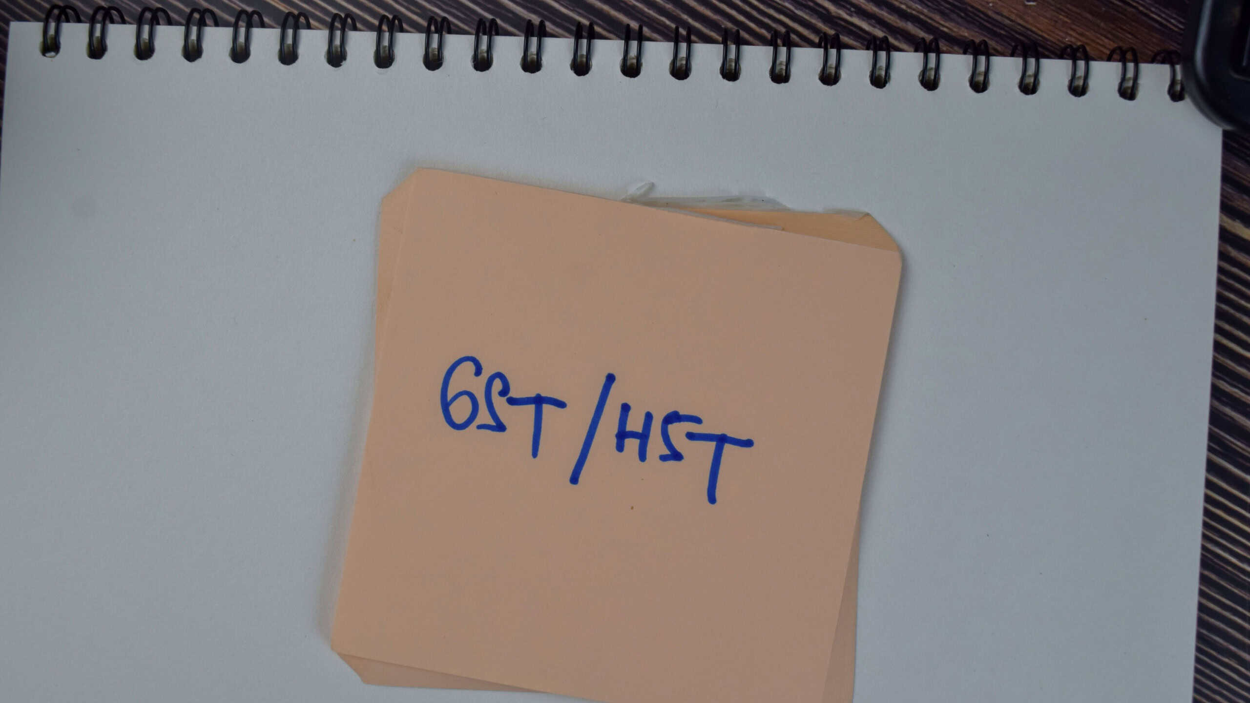 GST or HST write on sticky notes isolated on Wooden Table.
