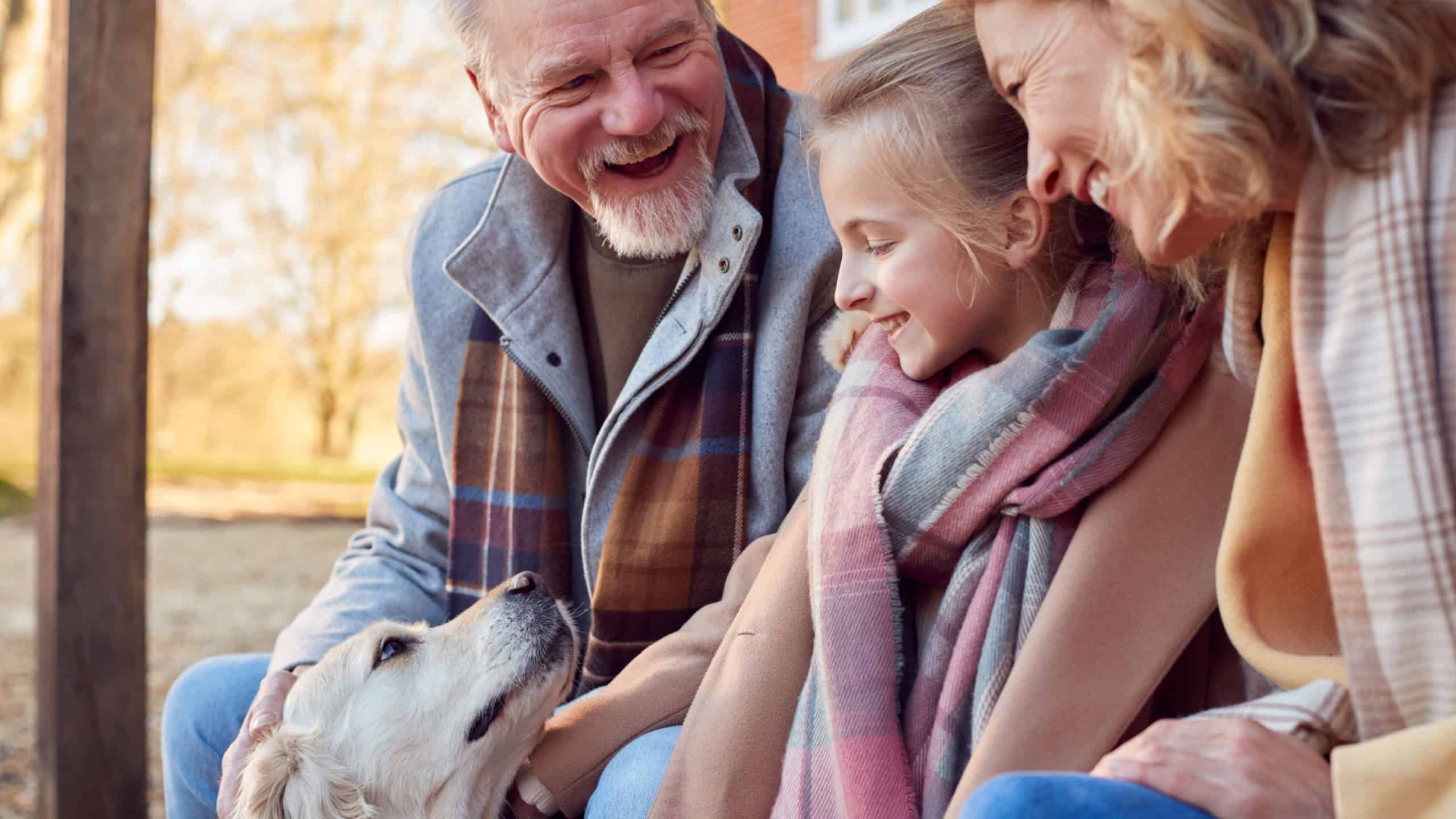 Grandparents With Granddaughter And Pet Dog Outside House Getting Ready To Go For Winter Walk
