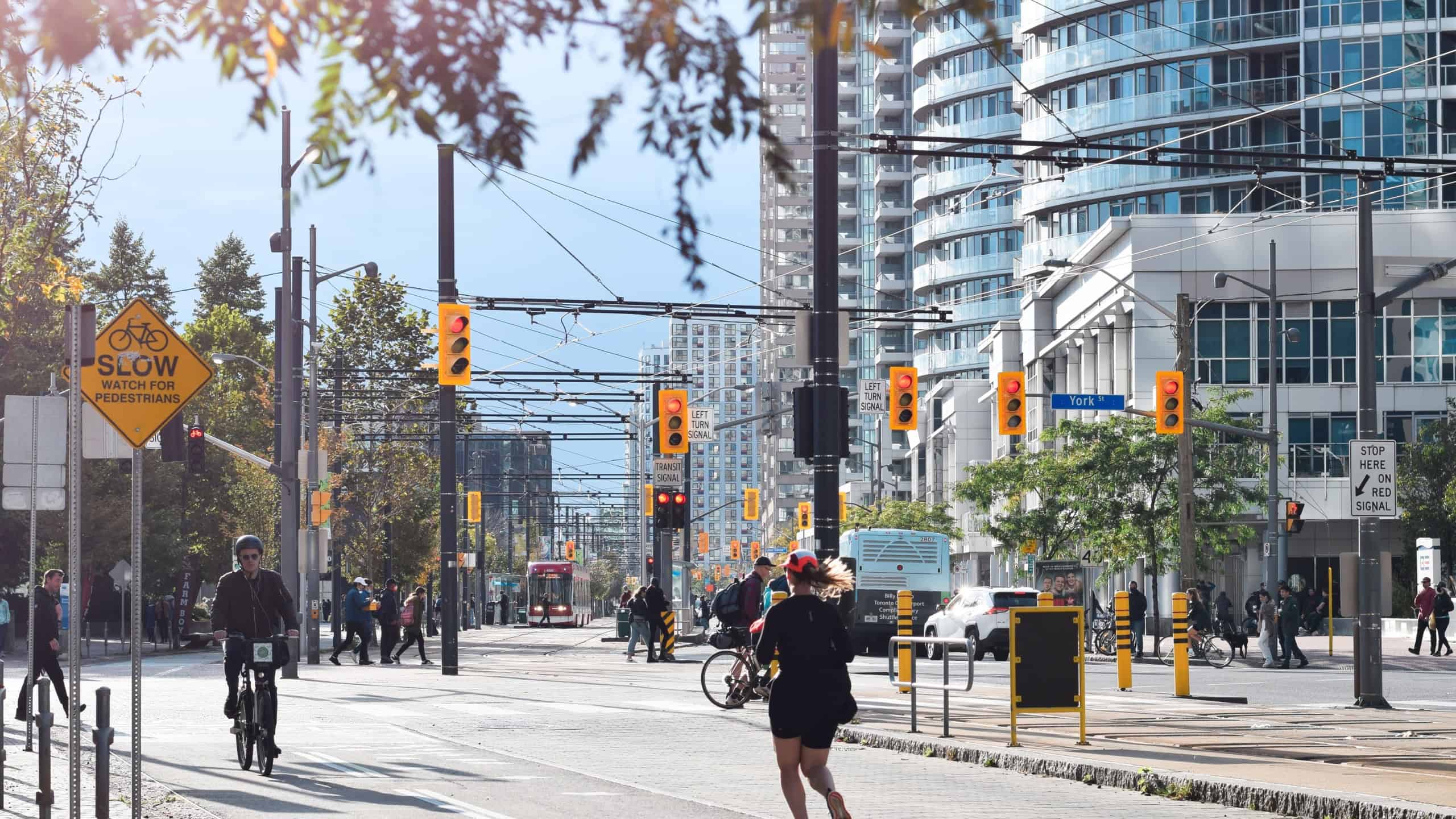Toronto, Ontario, Canada - October 17, 2021: People running and riding bicycles on bike path on Queens Quay waterfront downtown 
