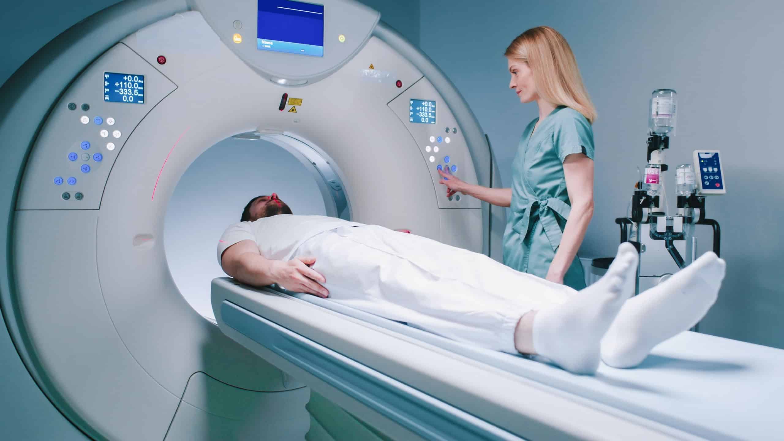 Patient is preparing for MRI examination. Man enters into MRI capsule. Female doctor calms patient and conducts magnetic resonance imaging. Medical worker is pressing buttons on MRI capsule.