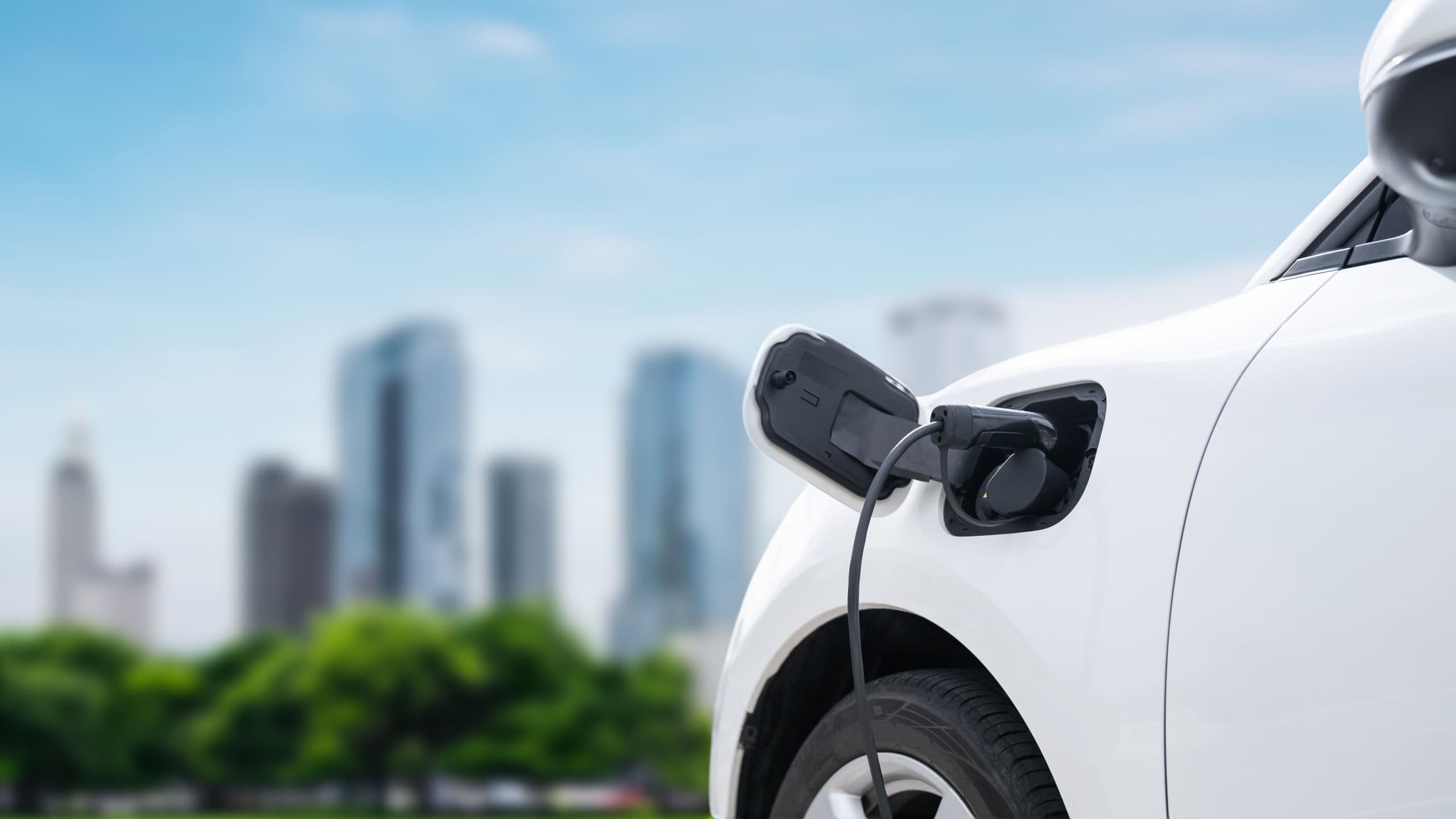 Focus closeup electric vehicle plugged in with EV charger device from blurred background of public charging station powered by renewable clean energy for cordial eco-friendly car concept.
