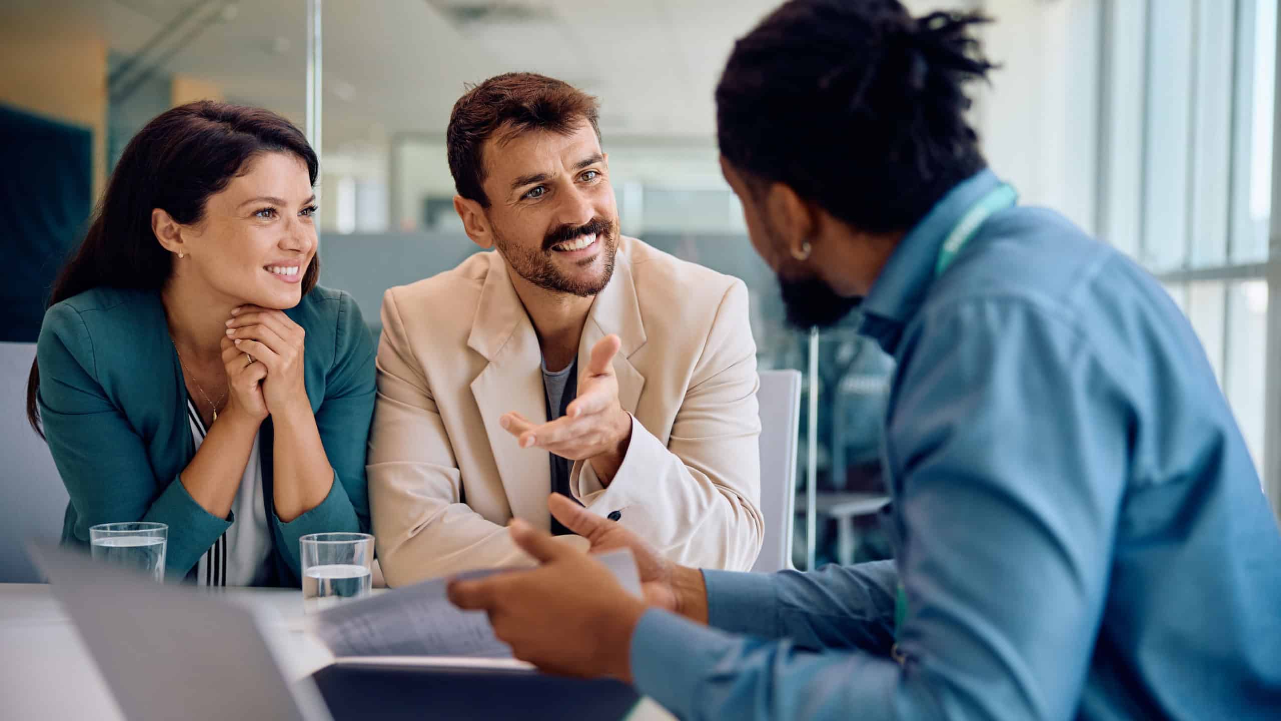 Happy man and his wife consulting with their insurance agent during a meeting in the office.