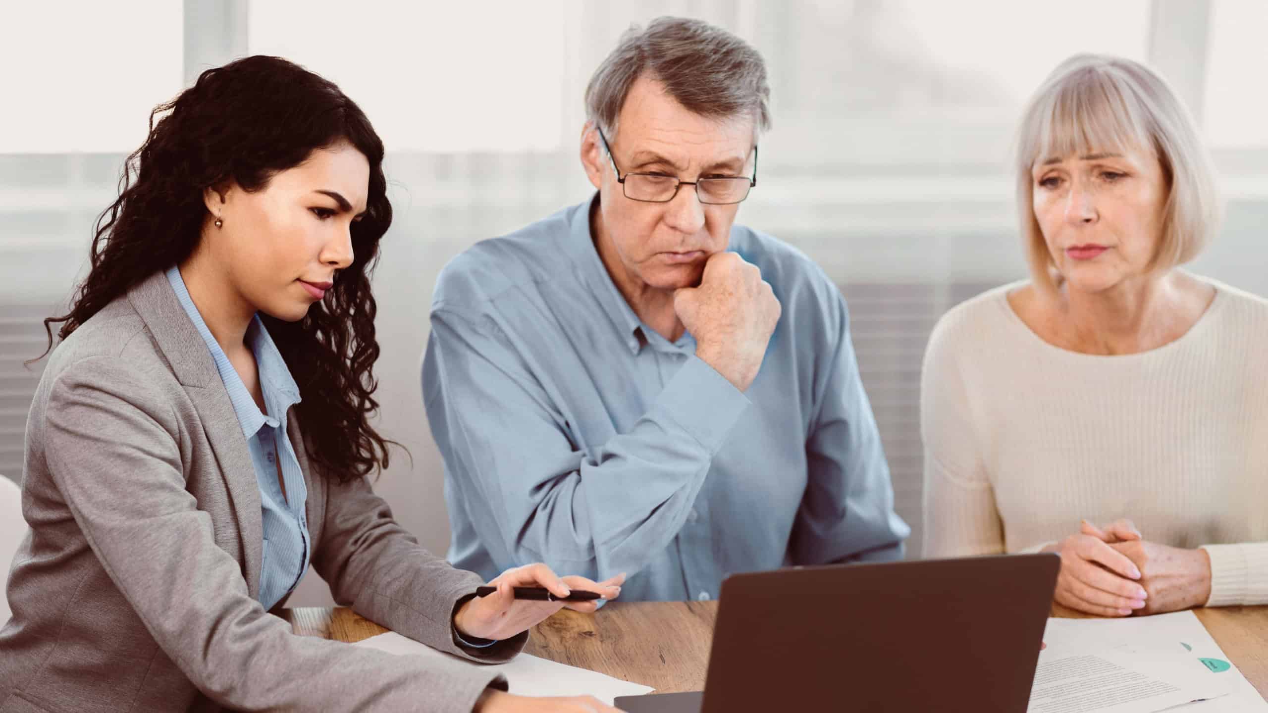 Insurance Concept. Sad senior couple consulting with female agent at office, using laptop computer