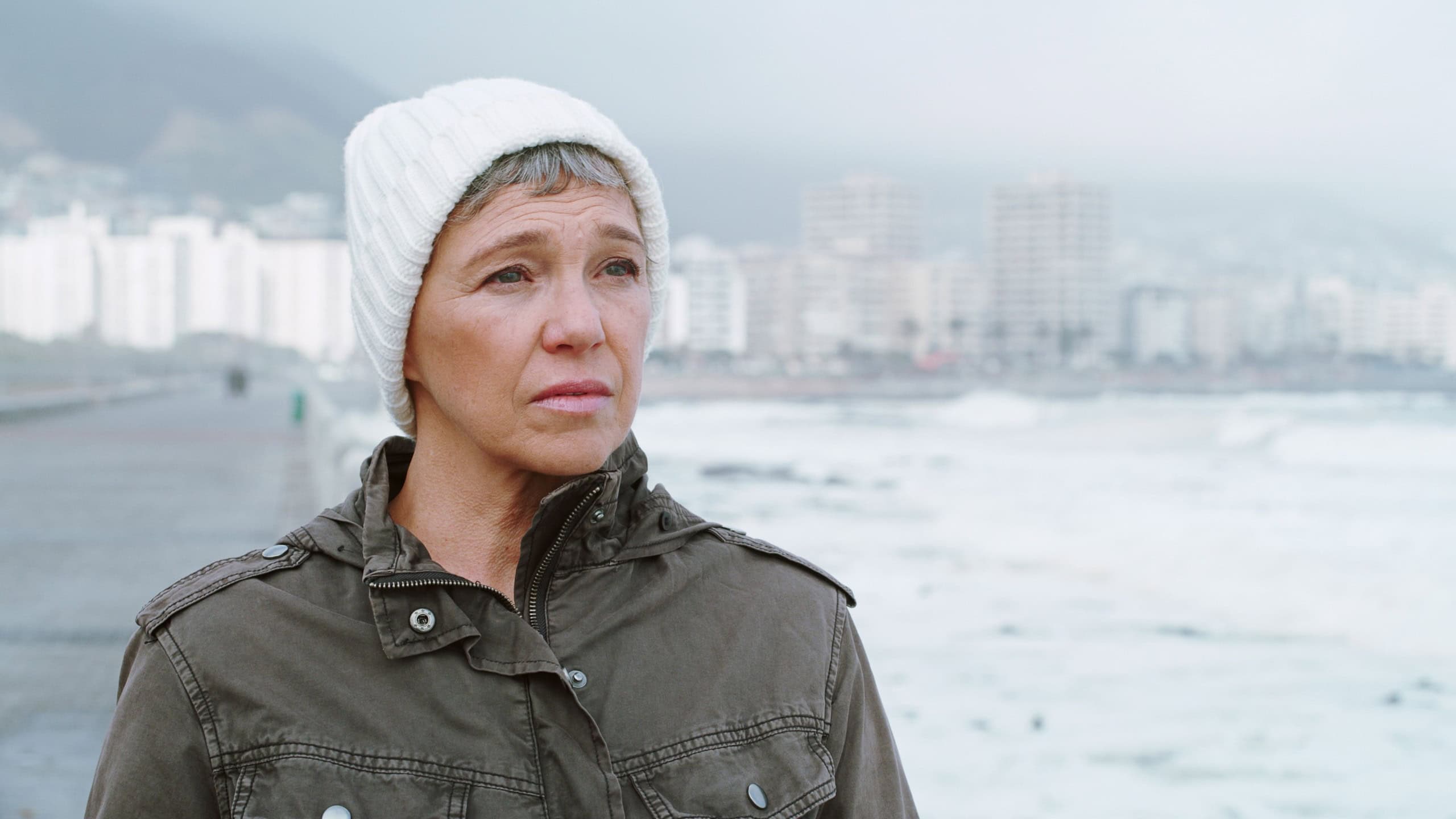 Sad, beach and mature woman with thinking, grief and loss outdoor with depression and mental health. Lonely, sea and winter vacation with travel, memory and bad news by ocean to remember the past