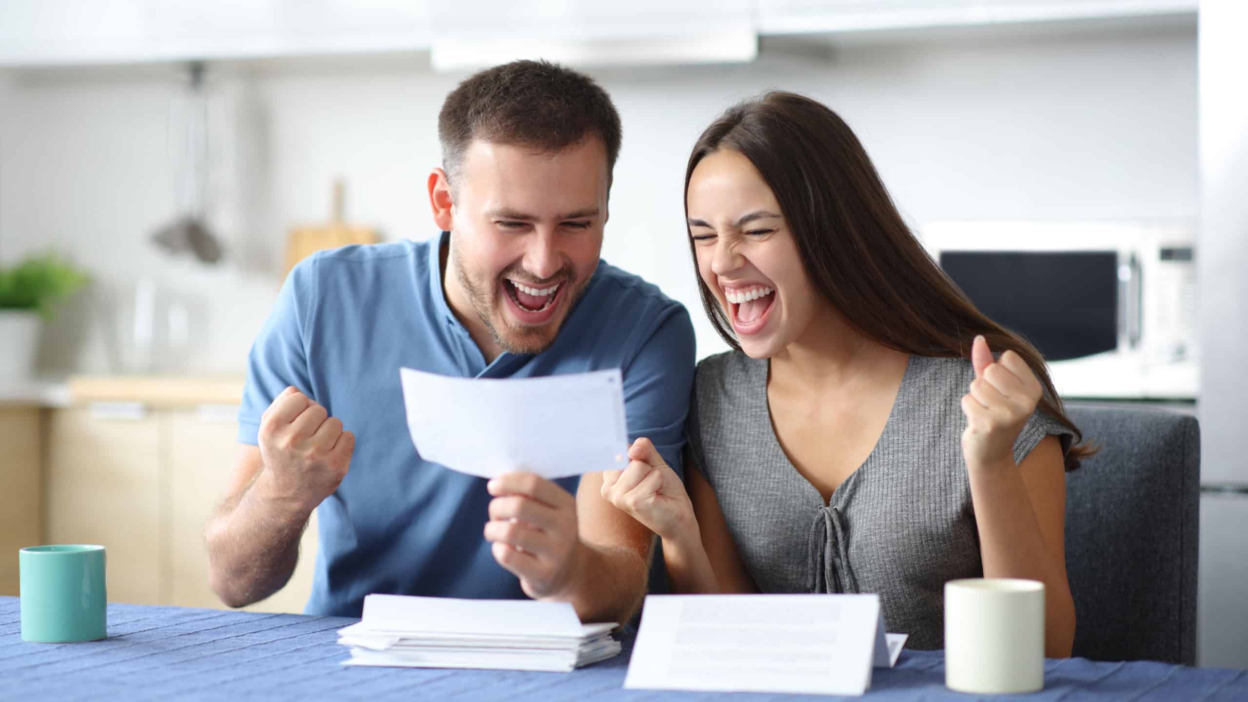 Excited couple checking bill in the kitchen at home