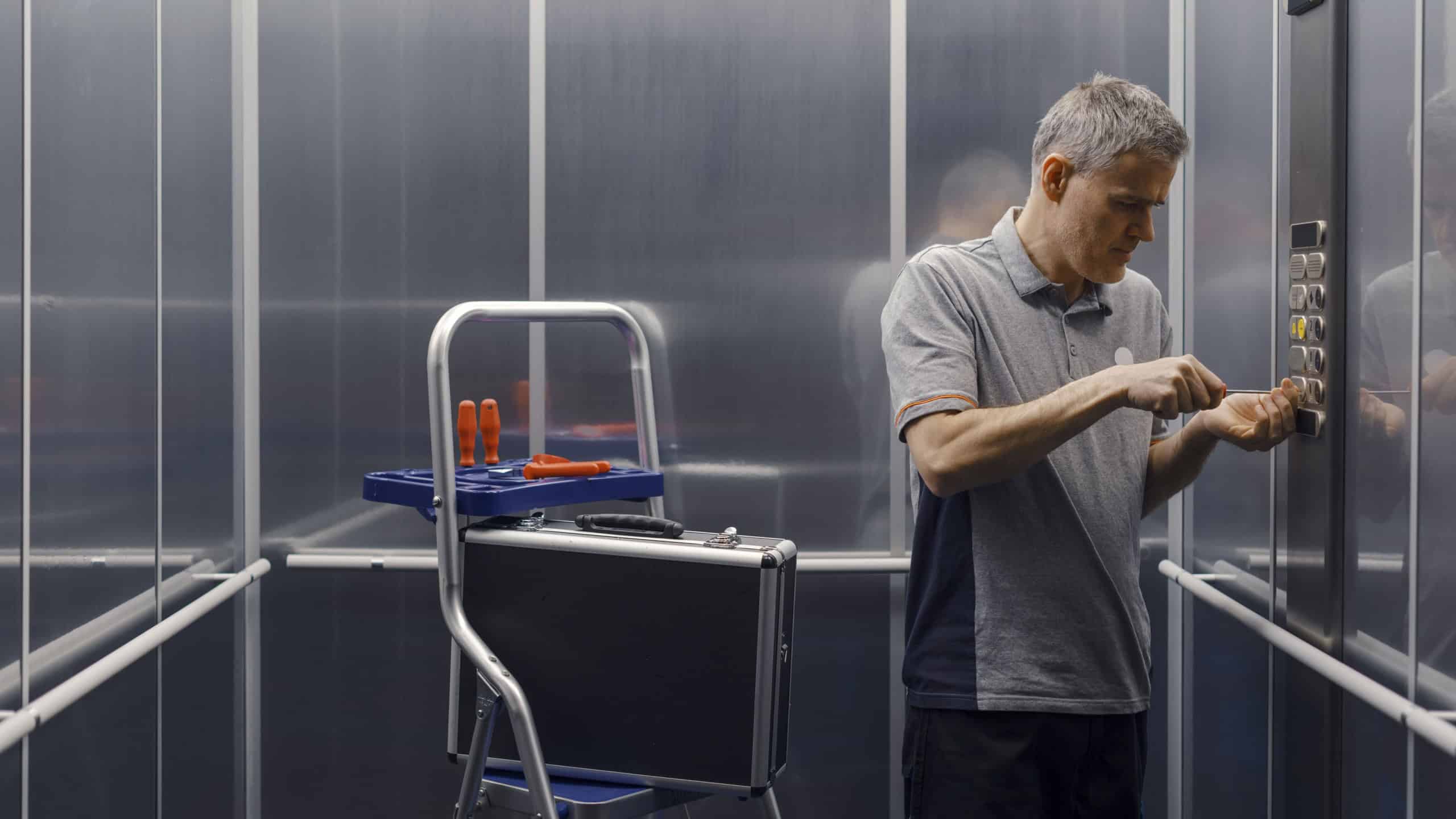 Professional elevator mechanic at work, he is checking and repairing the elevator control panel