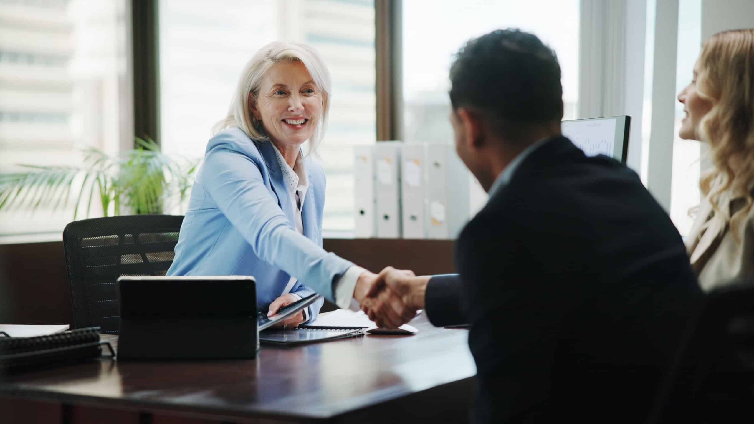 Business, woman and handshake with couple in office for finance consultation, debt management and welcome. Financial advisor, mature person and shaking hands in meeting for insurance planning or help