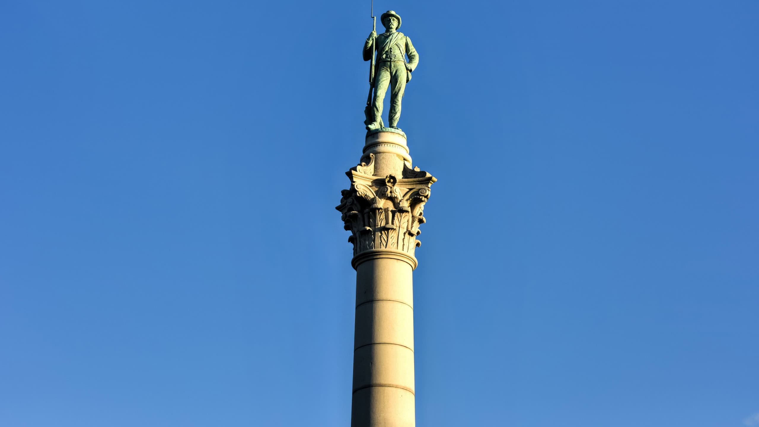 Confederate Soldiers' & Sailors' Monument. It depicts a bronze Confederate private standing on top of the pillar, which is composed of 13 granite blocks to symbolize each of the Confederate states.