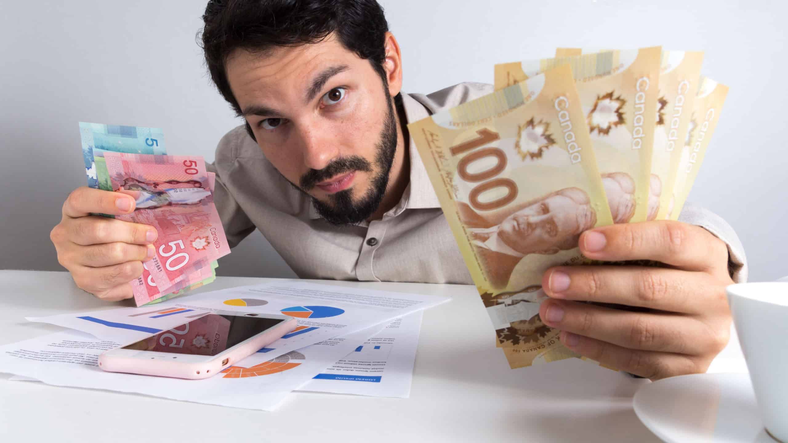 Paper notes from Canada. Dollar. Canadian cash. Young adult holding many bills on table.