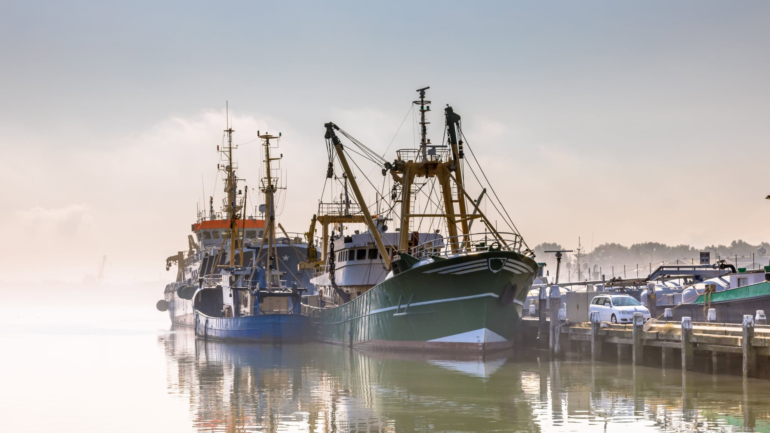 Modern fishing ships in hazy weather circumstances in harbour of Stellendam, Zeeland Province, the Netherlands.